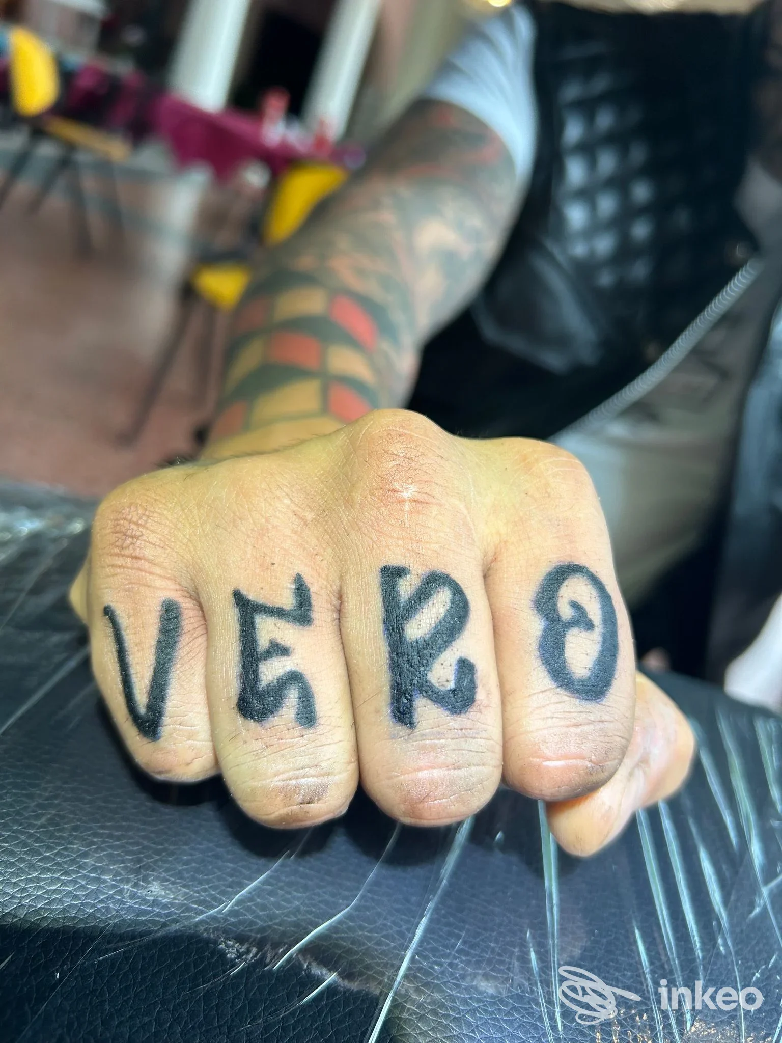 Primo piano di nocche tatuate con lettere nere 'VERO', mano appoggiata; Iron Ink Tattoo, Sassuolo.