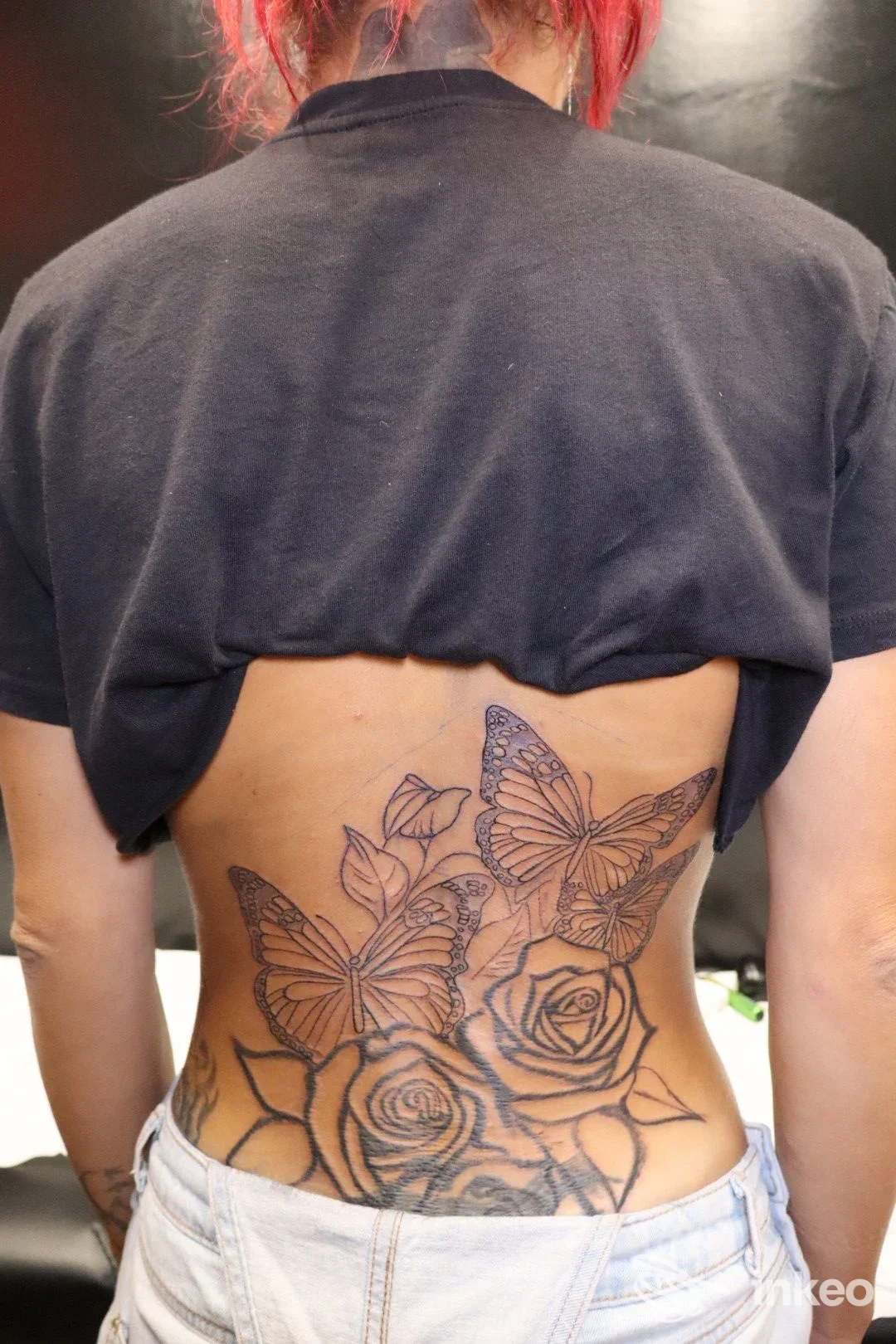 Ampio tatuaggio in linework con rose e farfalle sulla parte bassa della schiena, fotografato nello studio Iron Ink Tattoo a Sassuolo.