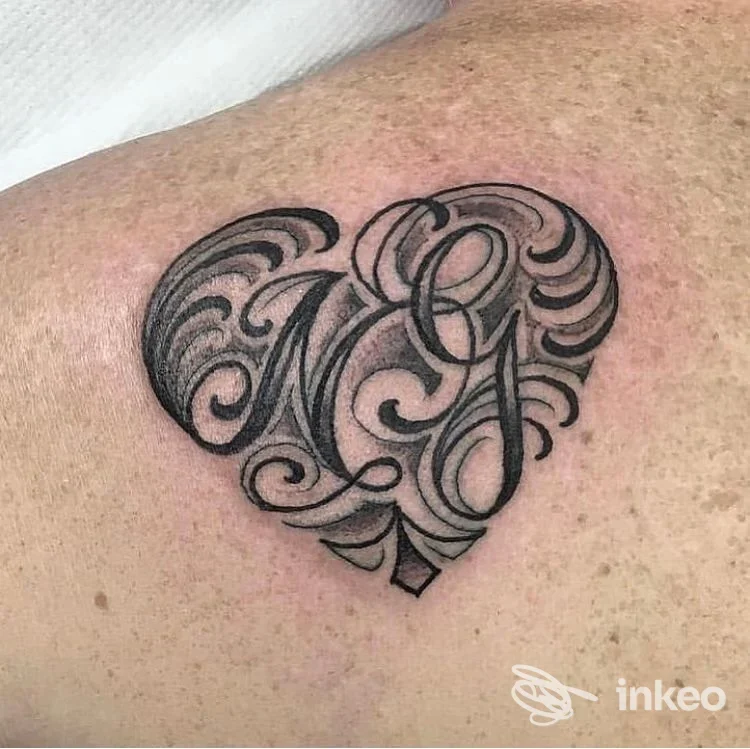 Tatuaggio a forma di cuore con iniziali in lettering e ombreggiature sul dorso/spalla, realizzato da Good Guys Tattooing a Forlì.