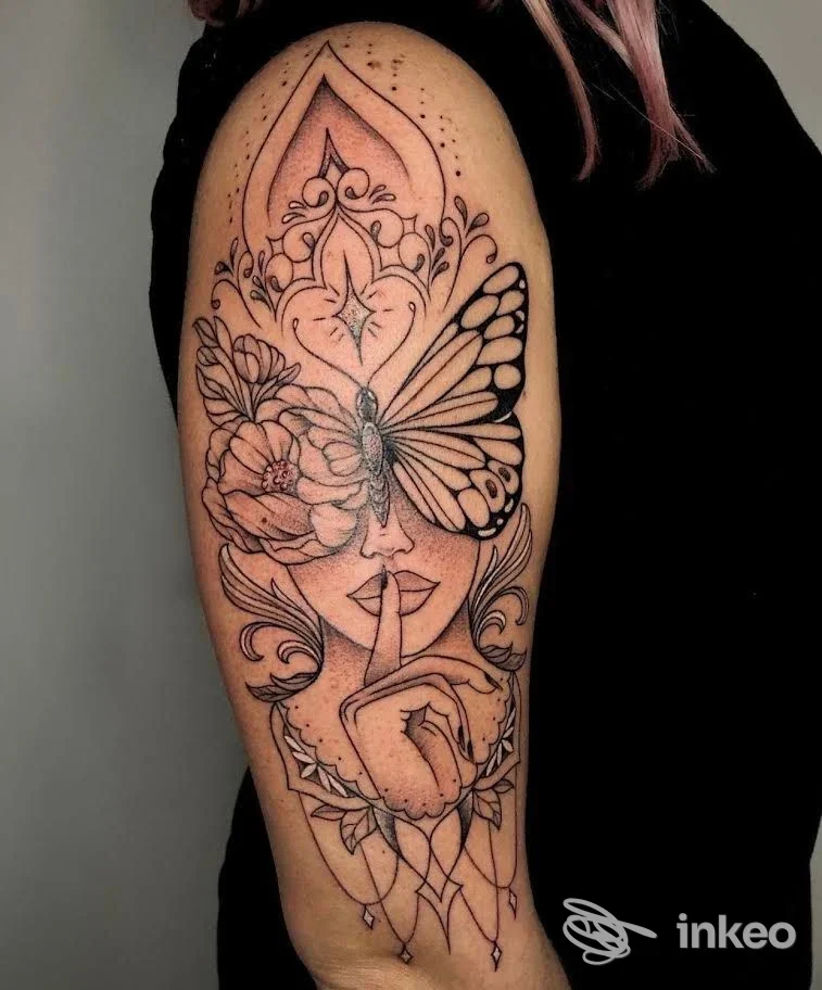Tatuaggio linework in nero sul braccio superiore con farfalla e volto stilizzato, opera condivisa da Danny Green Piercing & Tattoo a Carpi.