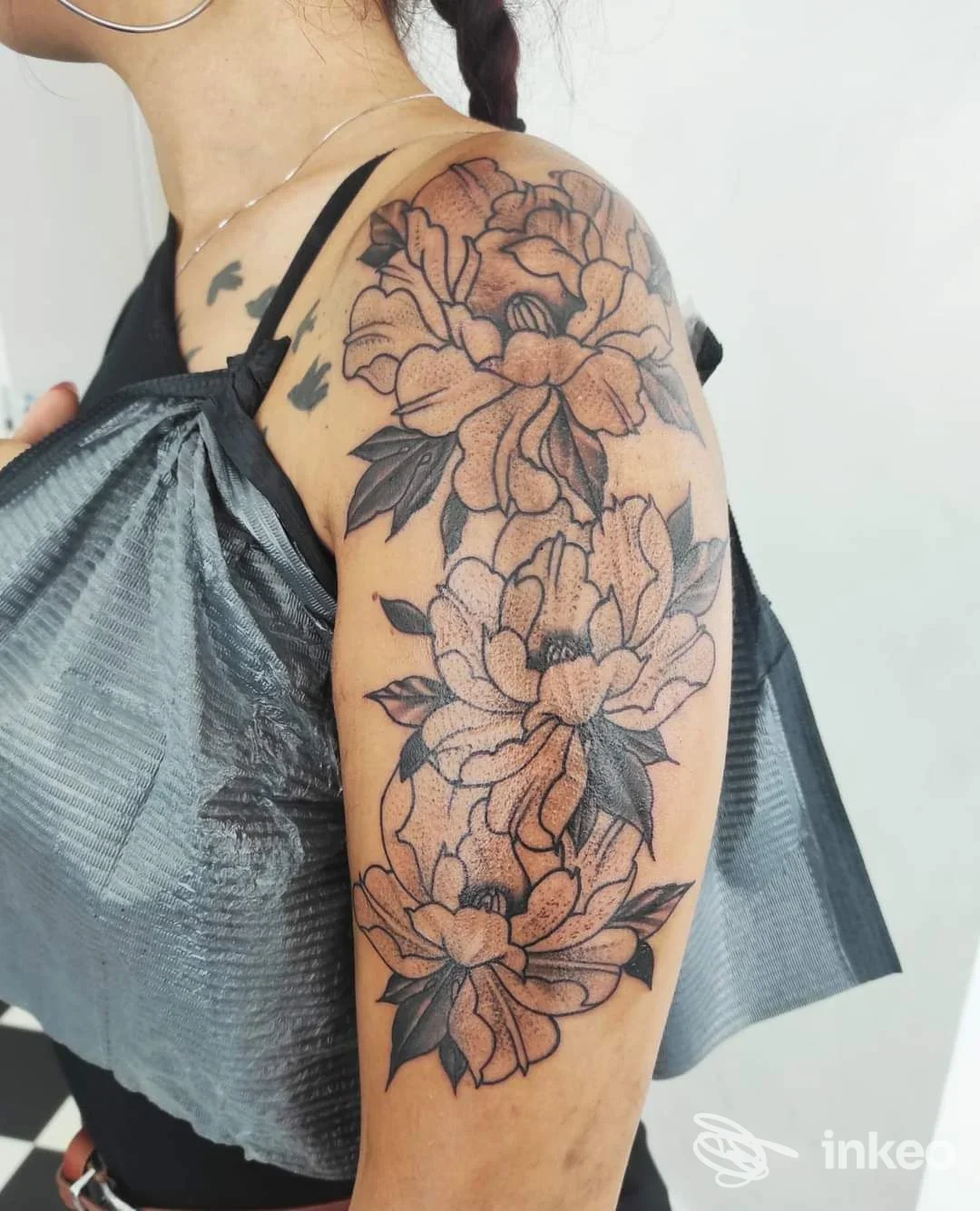 Tatuaggio floreale a inchiostro nero su spalla e braccio superiore, fotografia di Porka Loca Tattoo Studio a Ravenna.