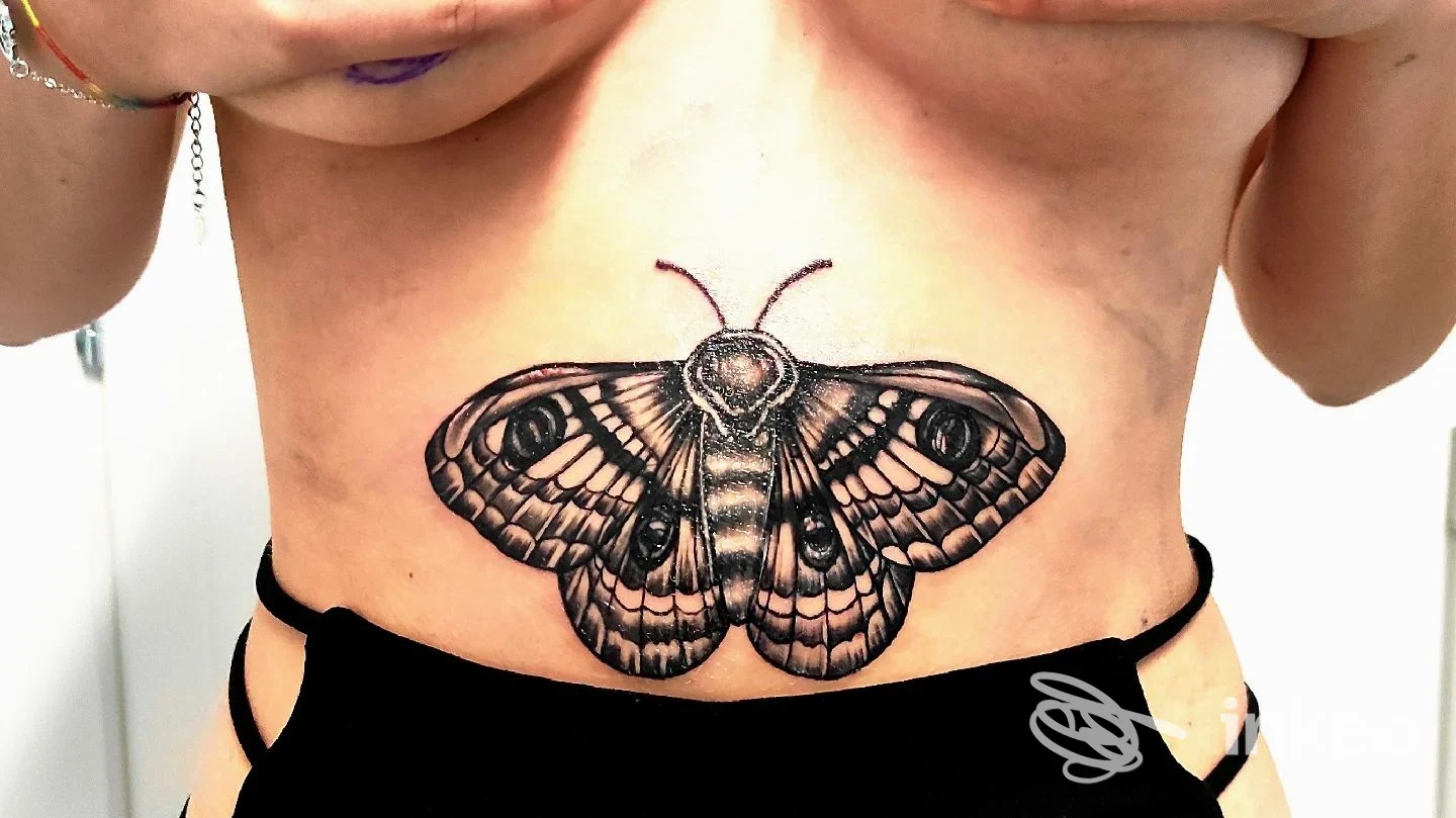 Grande tatuaggio a forma di falena sull'addome superiore, foto fornita da Porka Loca Tattoo Studio, Ravenna.