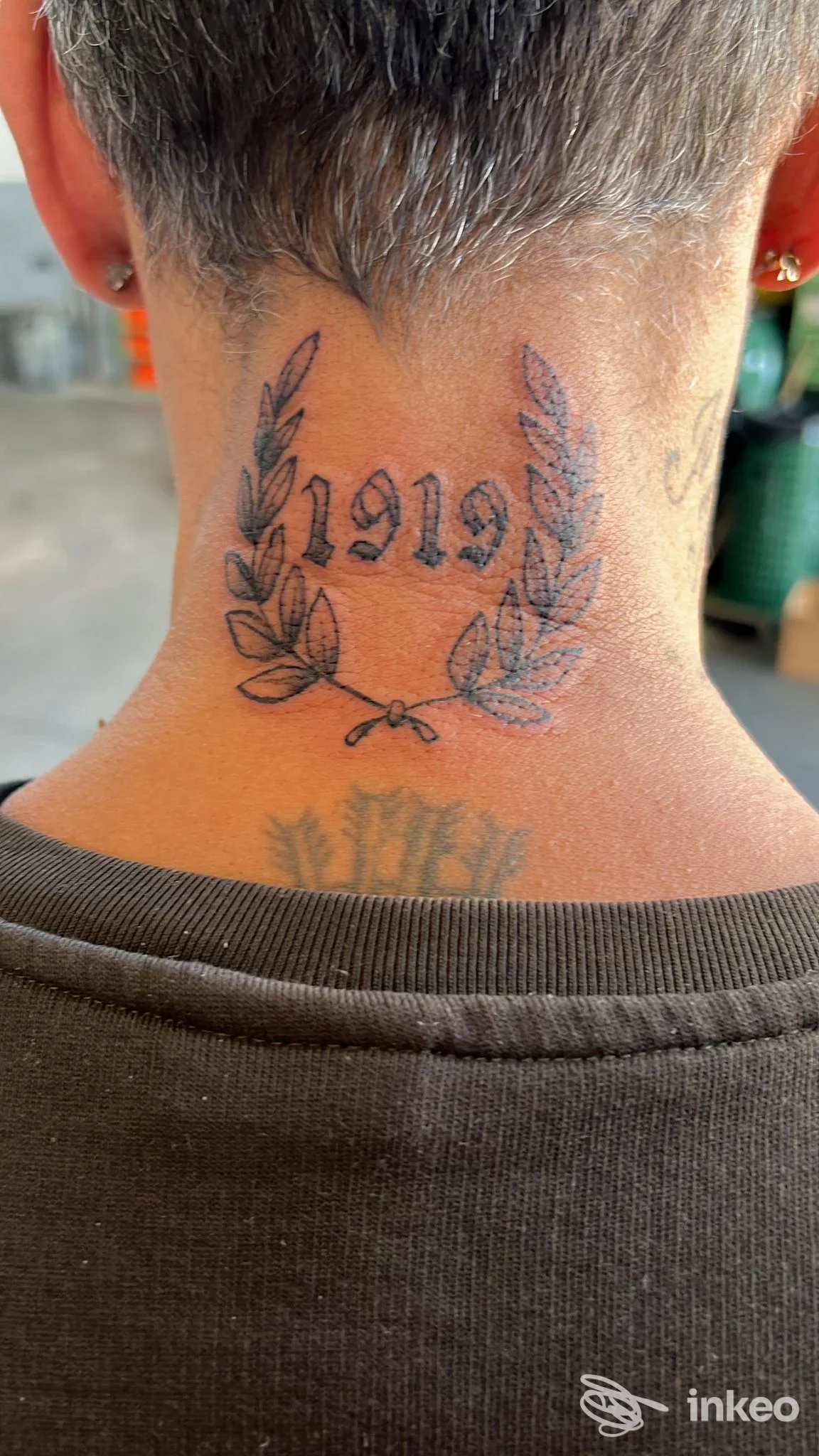 Dettaglio di tatuaggio a ghirlanda e scritta sulla nuca di un cliente, scattata presso Lauro Tattoo a Reggio nell'Emilia.