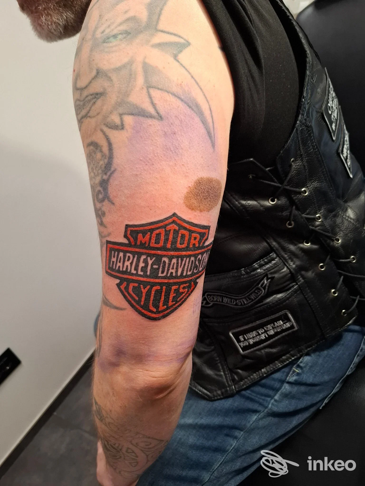 Tatuaggio con logo Harley‑Davidson sul braccio superiore, foto fornita da Lauro Tattoo a Reggio nell'Emilia.
