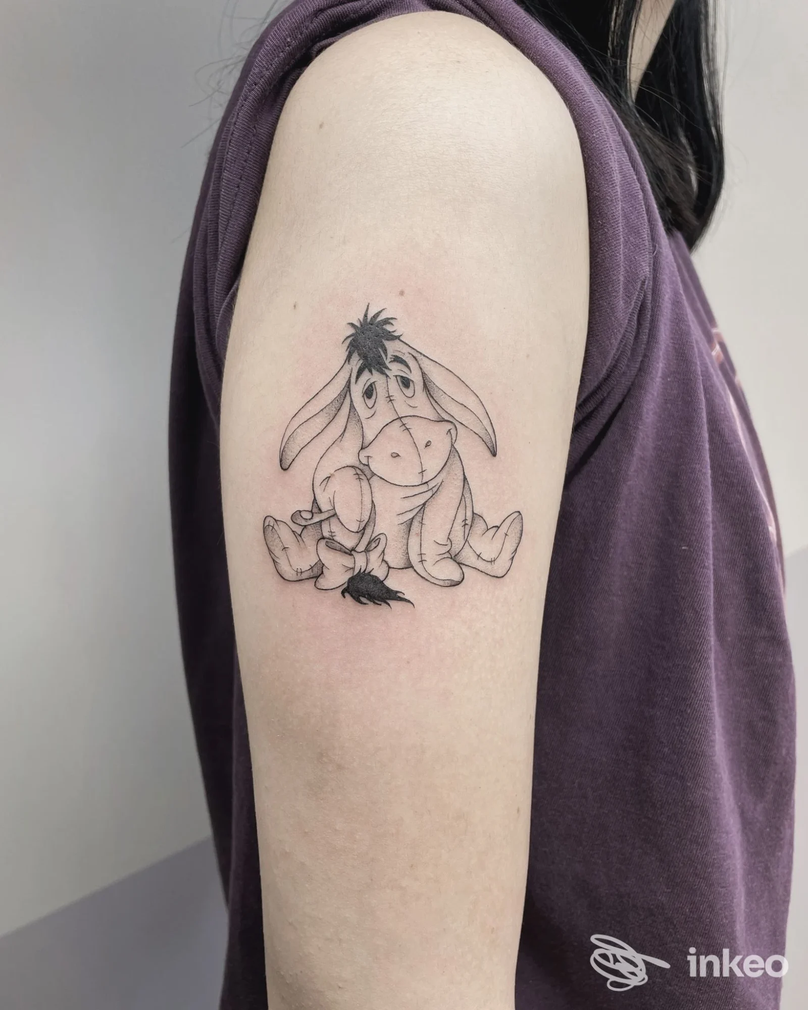 Tatuaggio in bianco e nero di un asino in stile cartone sul braccio superiore sinistro, foto fornita da Hills Road Tattoo Studio, Bibbiano.