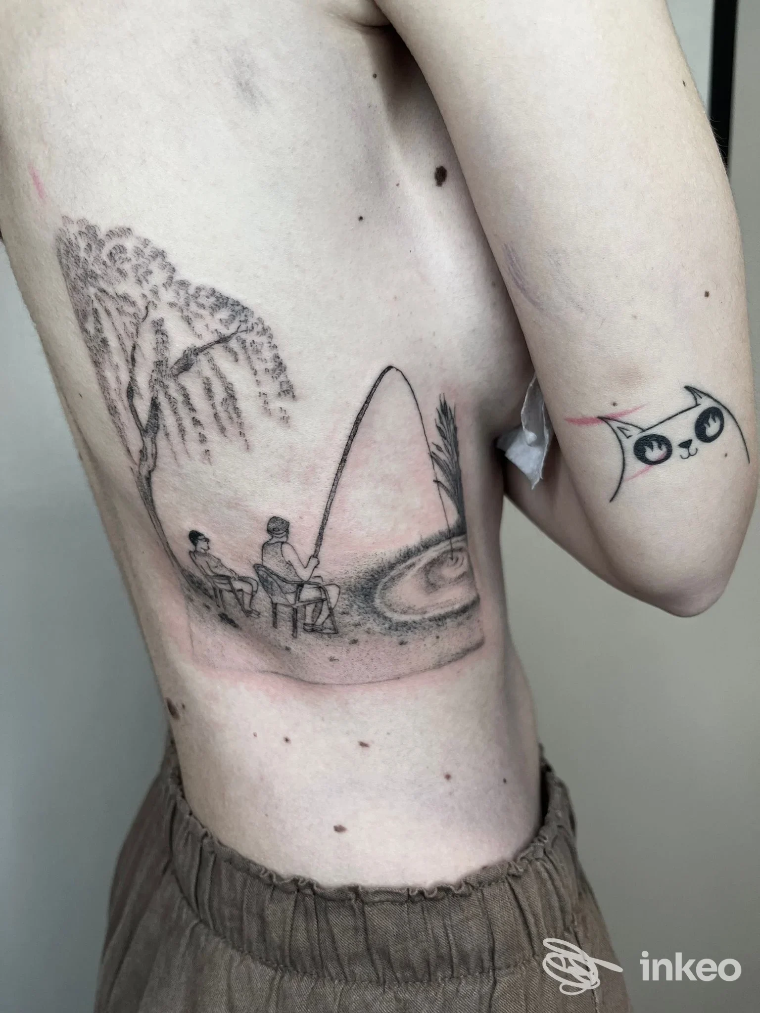 Tatuaggio figurativo in bianco e nero sul fianco con coppia che pesca, LaRossiTattoo, Bellaria-Igea Marina.