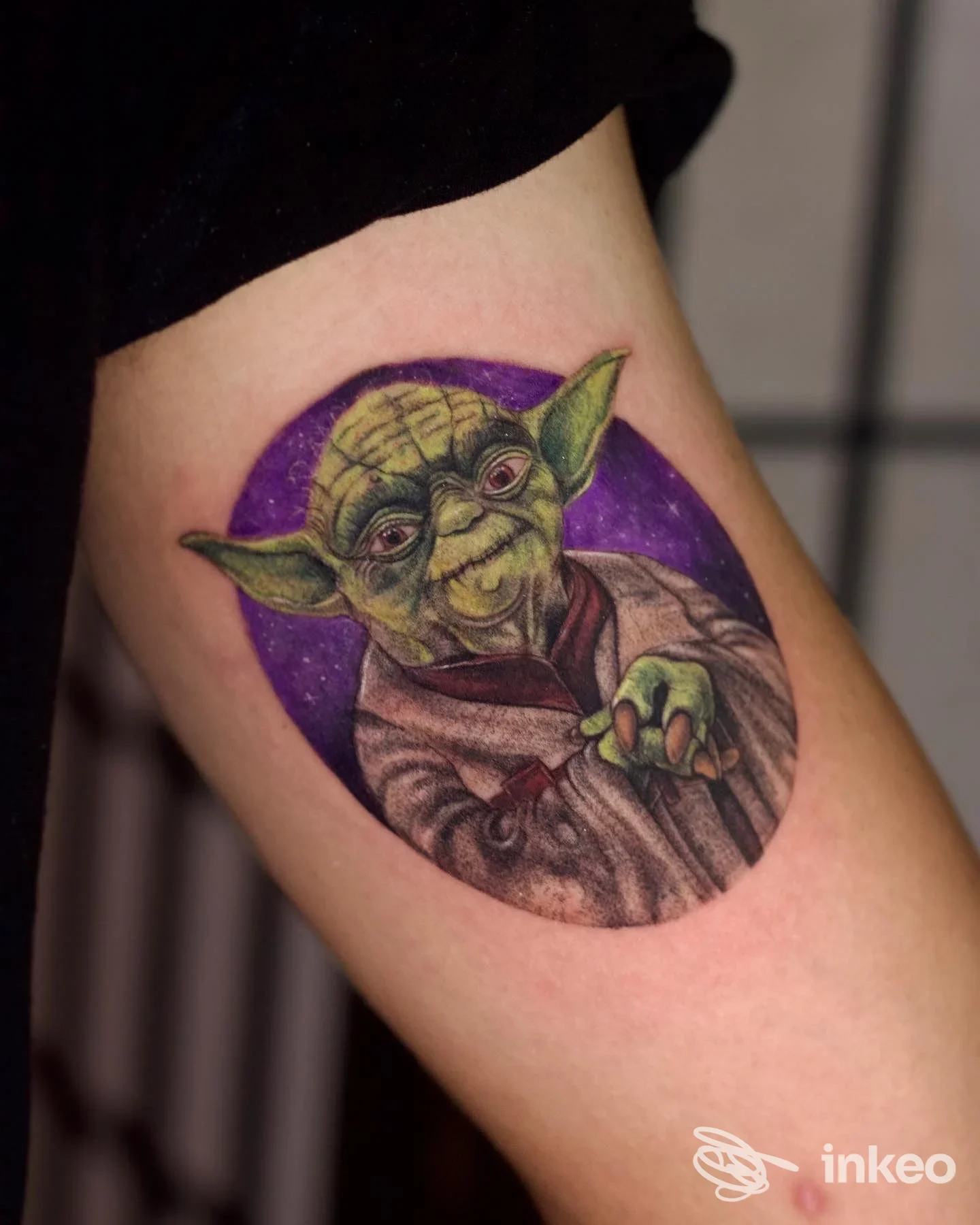 Tatuaggio a colori raffigurante Yoda su sfondo viola, posizionato sul bicipite; Vily Tattoo Studio, Carpaneto Piacentino.