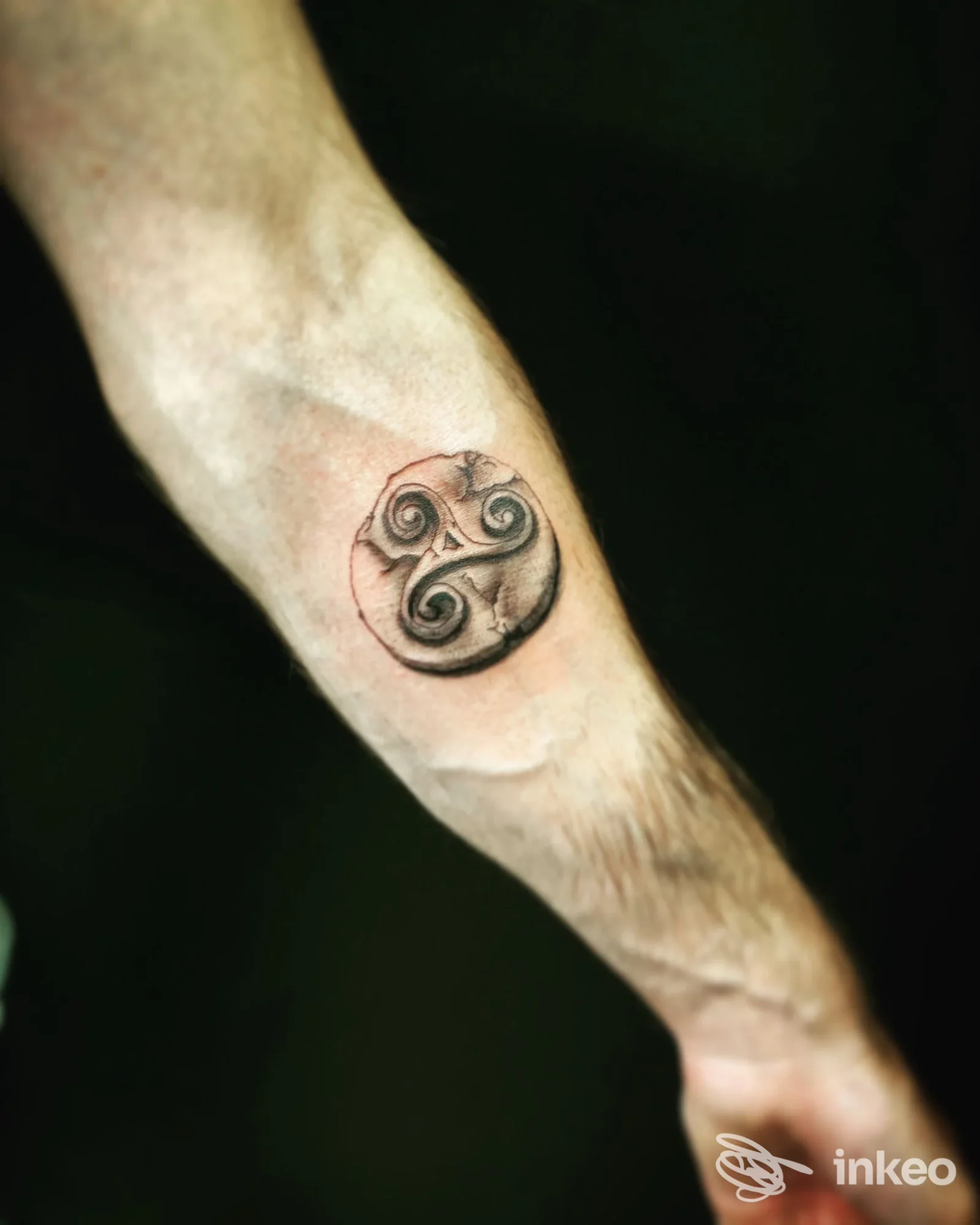 Tatuaggio circolare con motivo a spirale sull'avambraccio, realizzato su pelle chiara; design nero con dettagli ad intreccio, eseguito da AliceFox Tattoo.