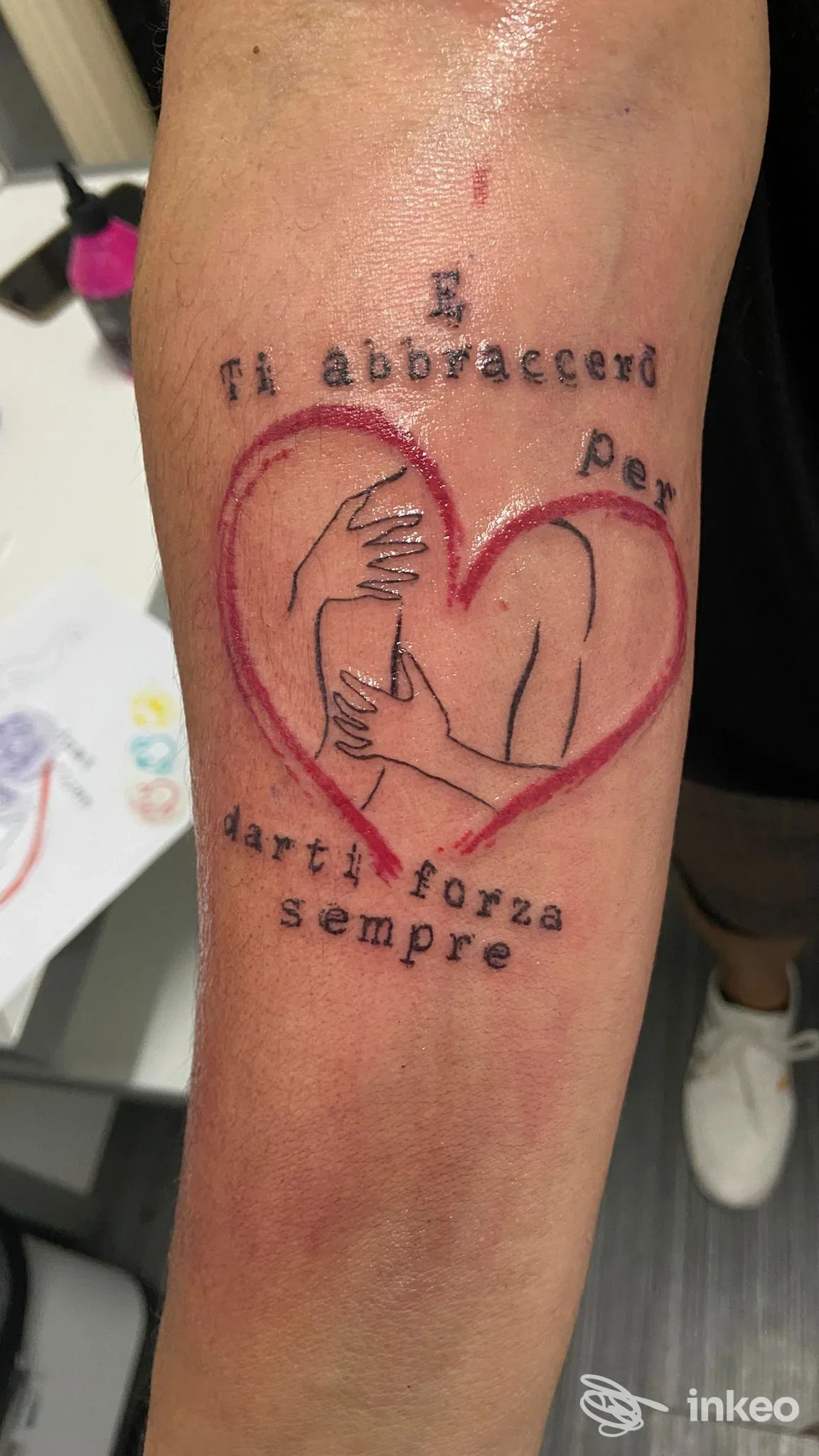 Tatuaggio fresco su avambraccio con cuore rosso e figure stilizzate abbracciate; lavoro fotografato presso Black Sin Tattoo Studio, Cesena.