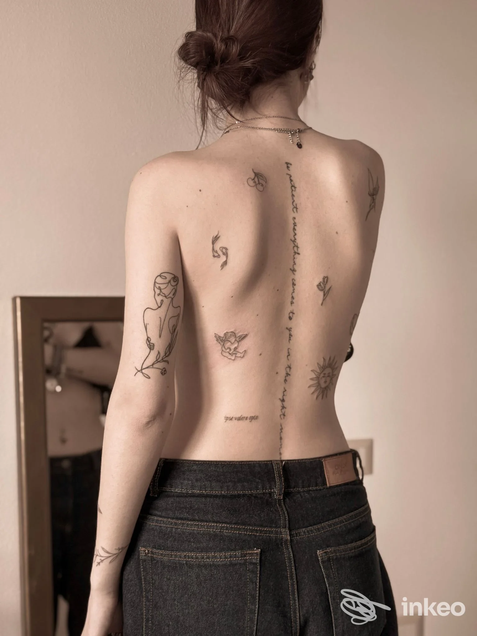 Schiena nuda con diversi tatuaggi sottili lungo la colonna vertebrale e sugli avambracci, foto fornita per Secret Ink Tattoo a Longiano.
