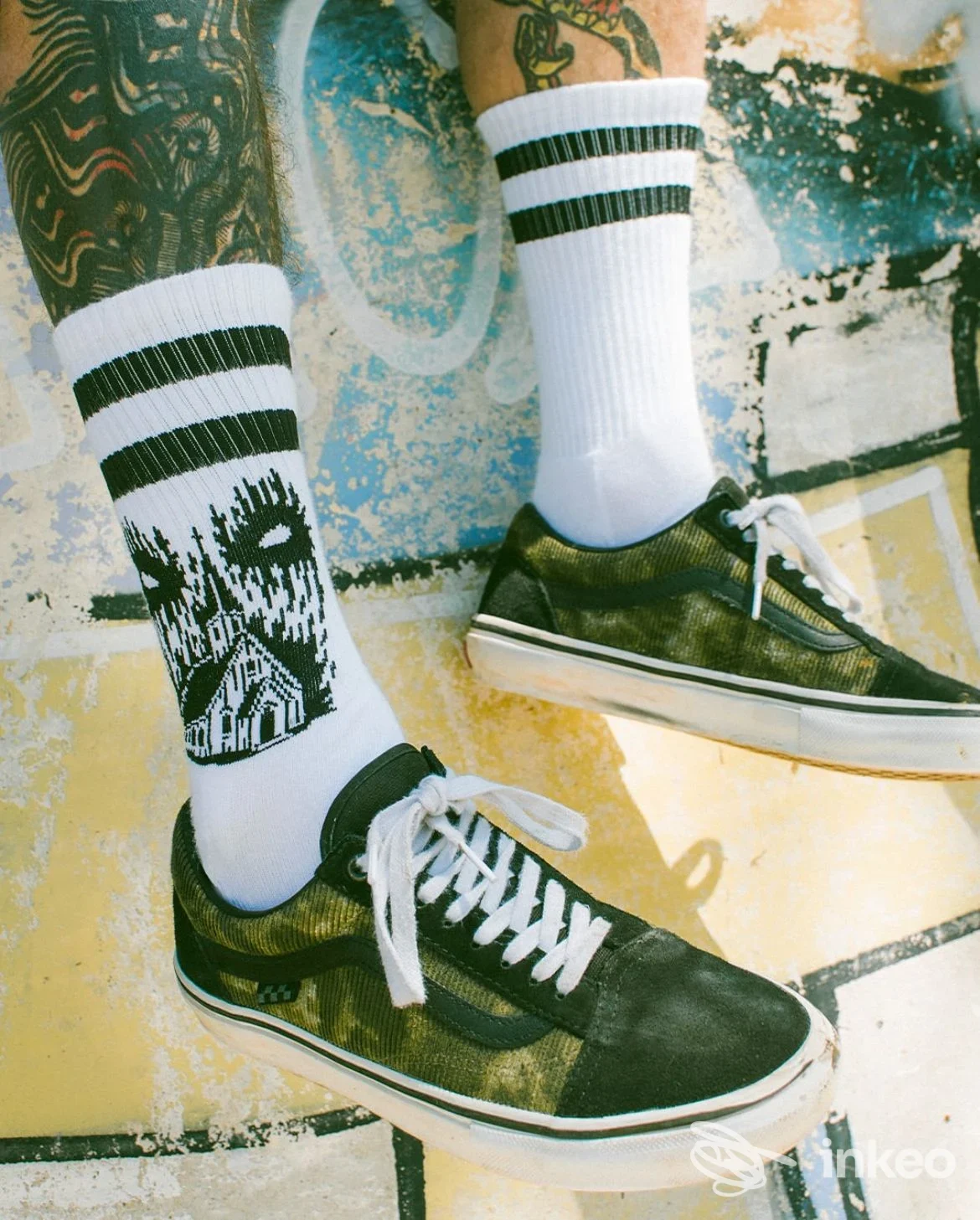 Dettaglio di gambe tatuate con calzini e sneakers — immagine per Homeless Tattoo Piercing & Streetwear, Piacenza.