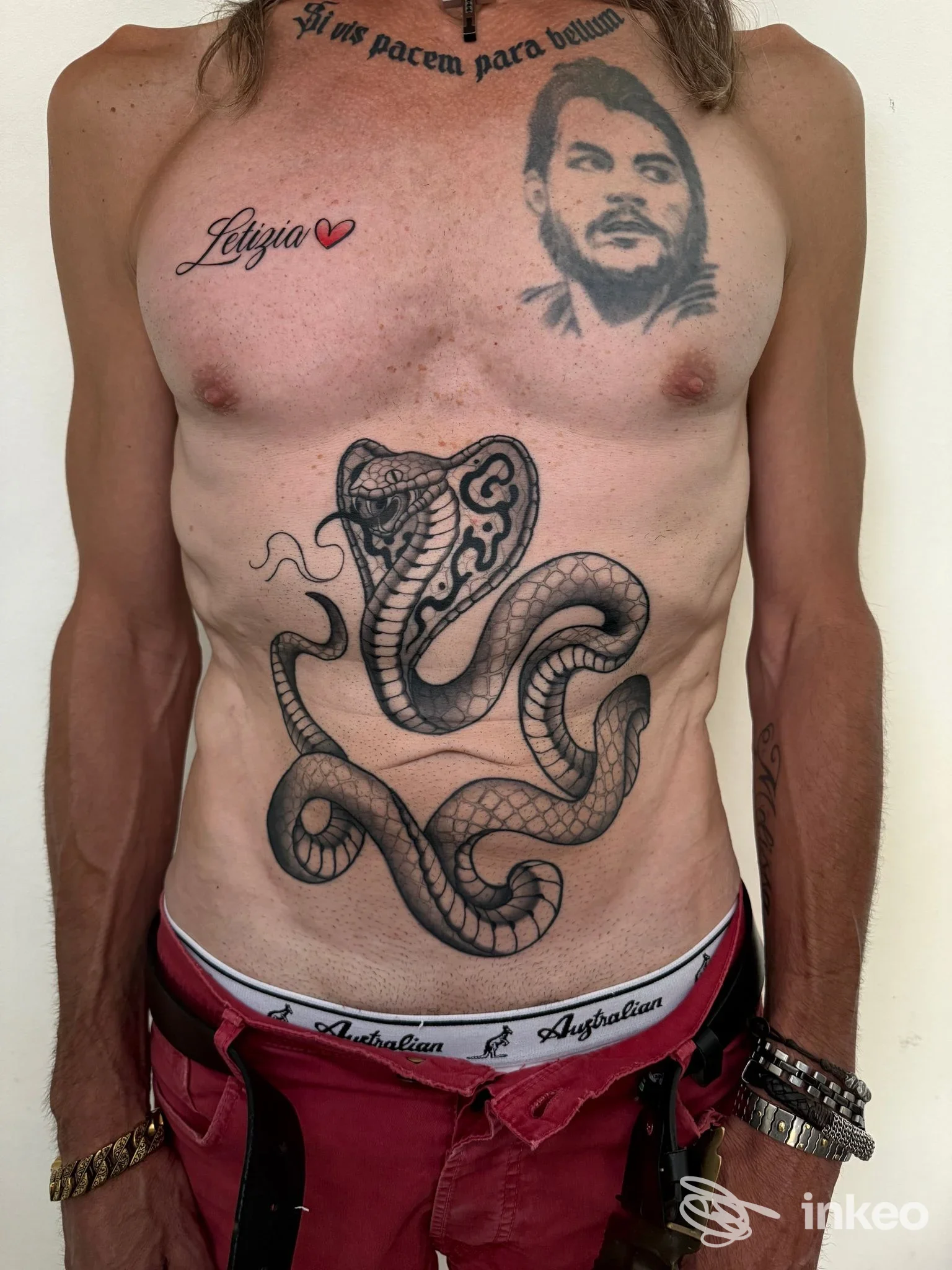 Tatuaggi su torso con grande serpente sull'addome, ritratto e scritta sul petto — Sole nero tattoostudio, San Mauro Pascoli.