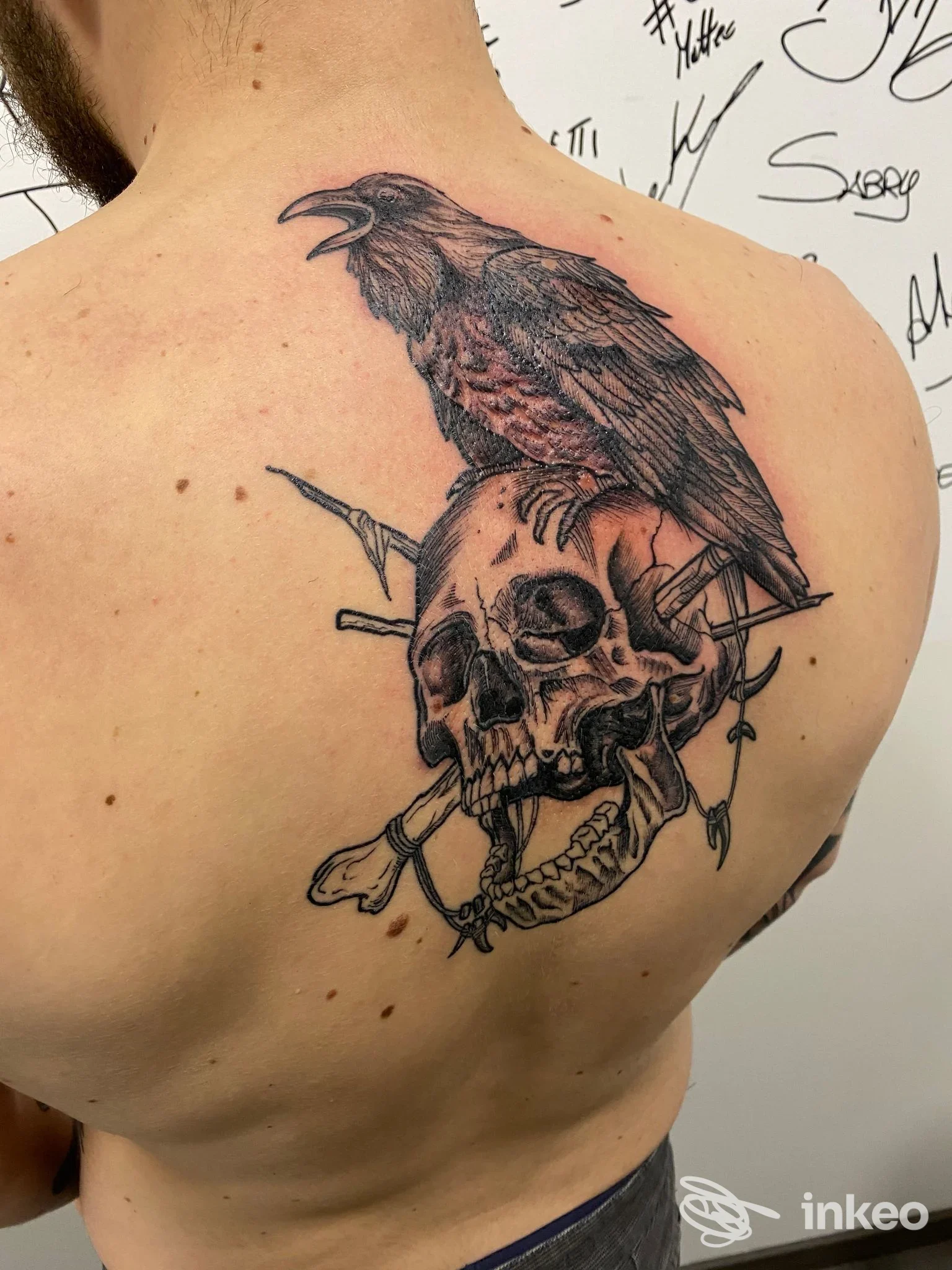 Grande tatuaggio nero con teschio e corvo sulla parte superiore della schiena, foto fornita da Cuore Nero Tattoo a Fornace.
