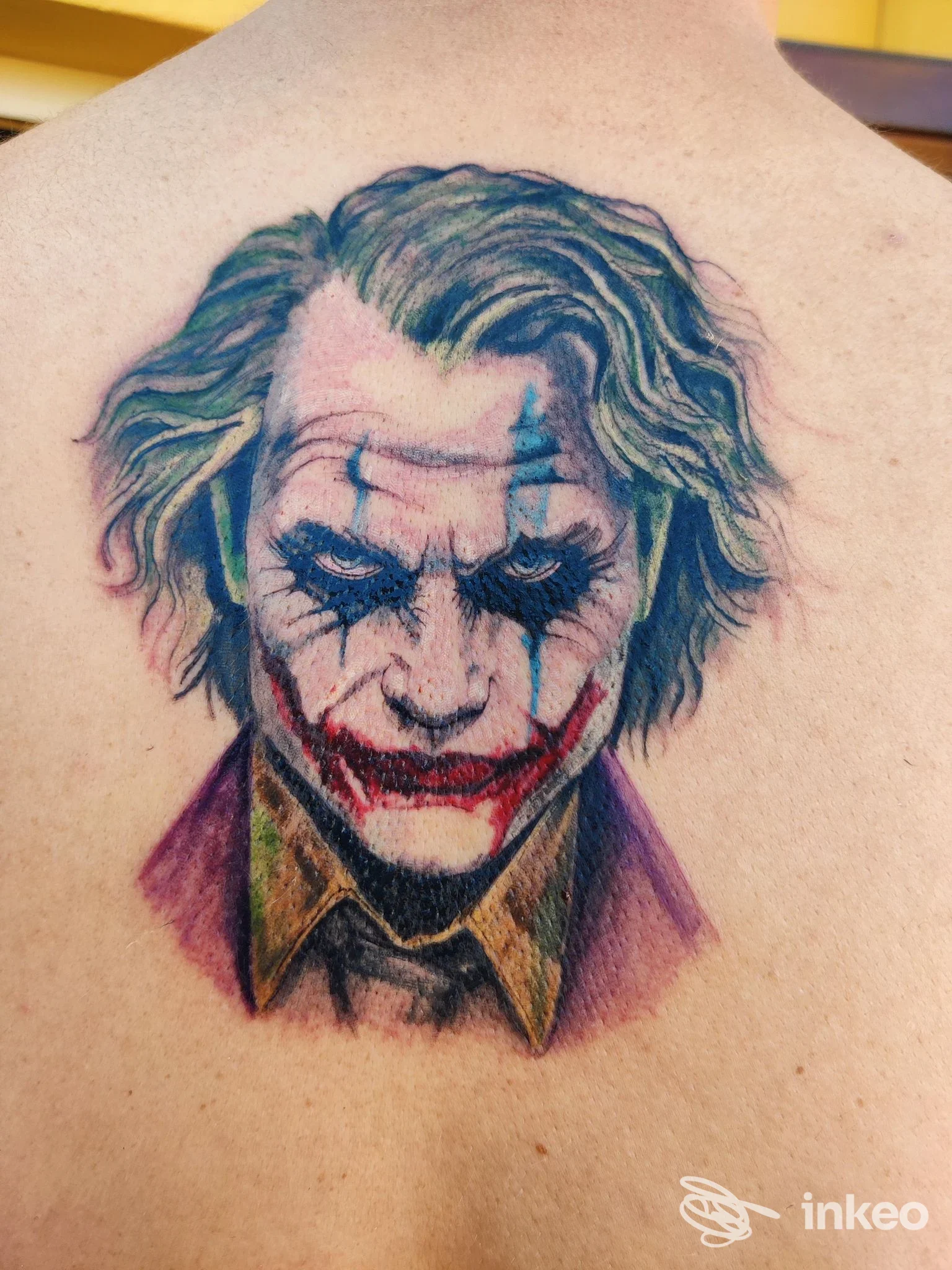 Tatuaggio ritratto del Joker sulla parte superiore della schiena, realizzato da InkWish a Cattolica.