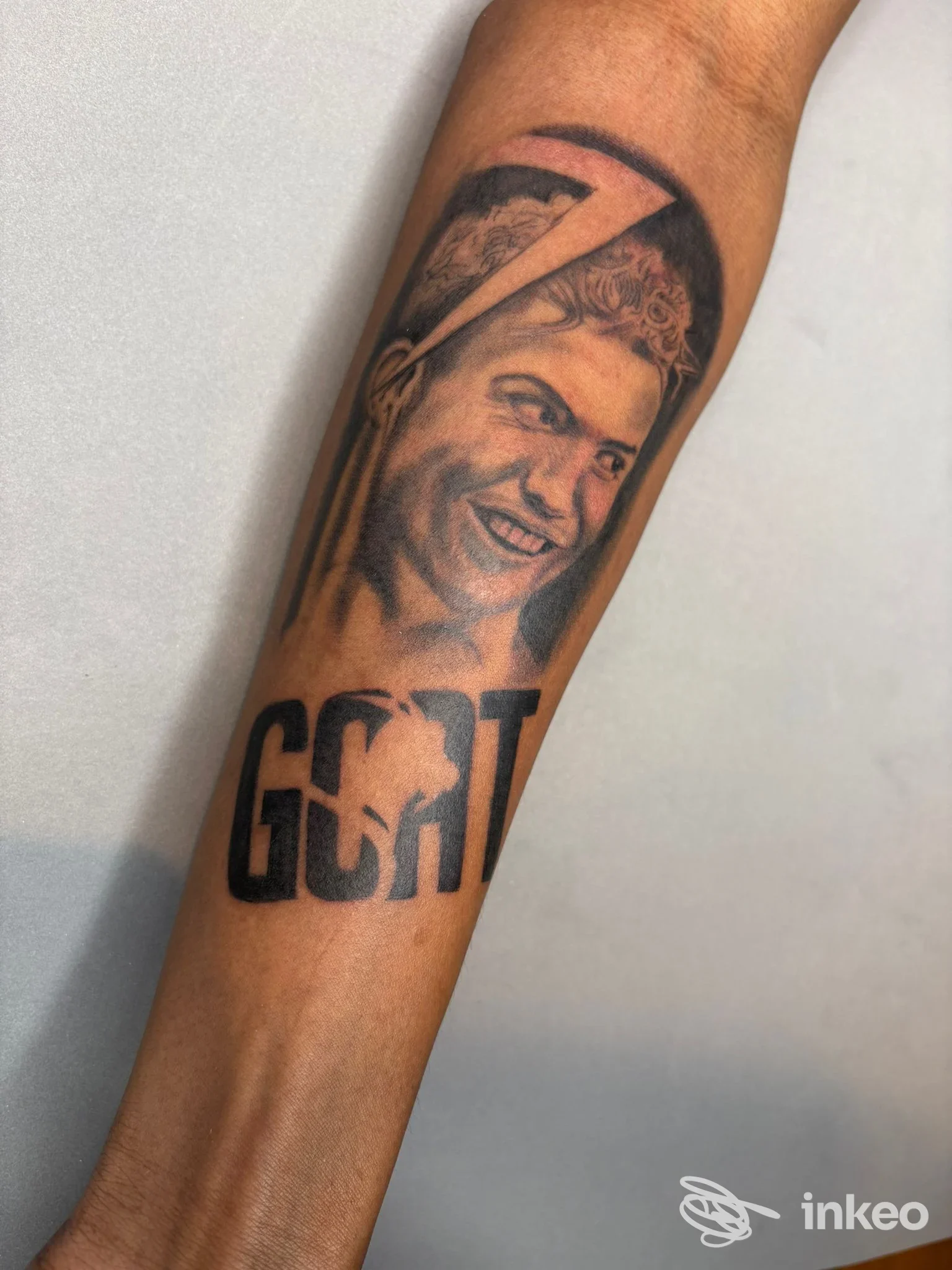 Tatuaggio ritratto realistico sull'avambraccio con la scritta 'GOAT', opera condivisa da Joker Tattoo a Reggio nell'Emilia.