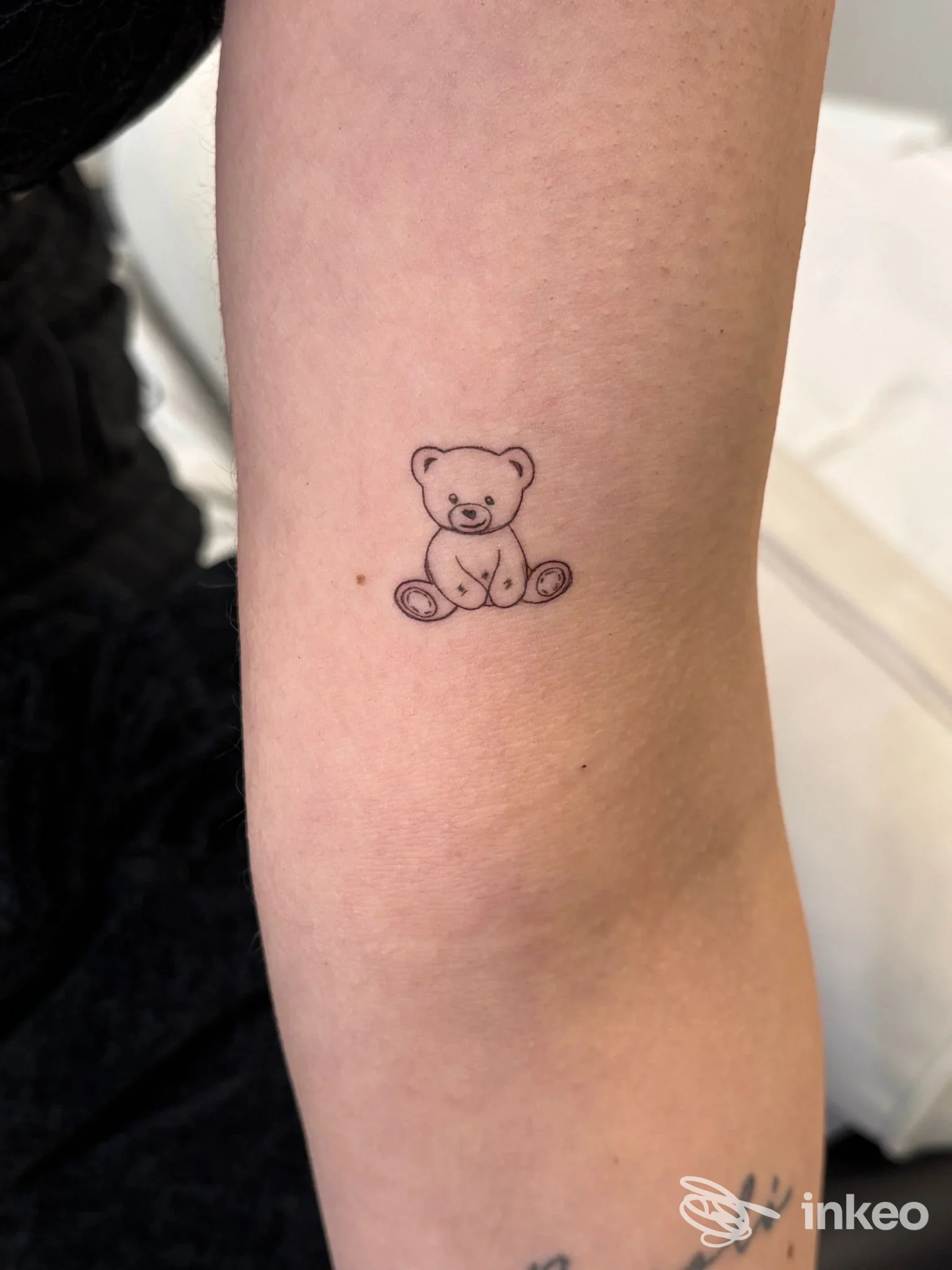 Un piccolo tatuaggio di orsetto su pelle umana, situato sull'avambraccio; nessun volto visibile, nessuna interfaccia sociale apparsa.