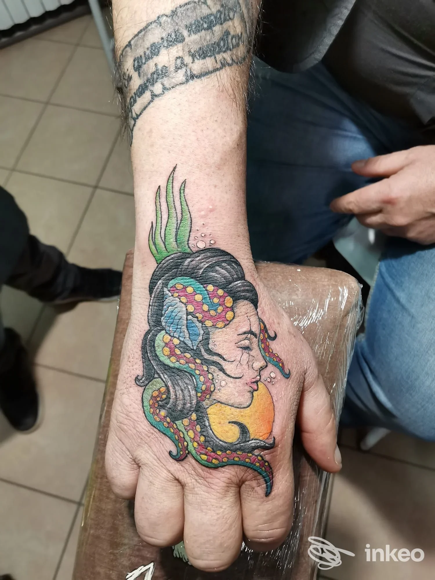 Tatuaggio a colori su mano con profilo femminile e tentacoli, foto fornita da Vintage Tattoo Shop, Ferrara.