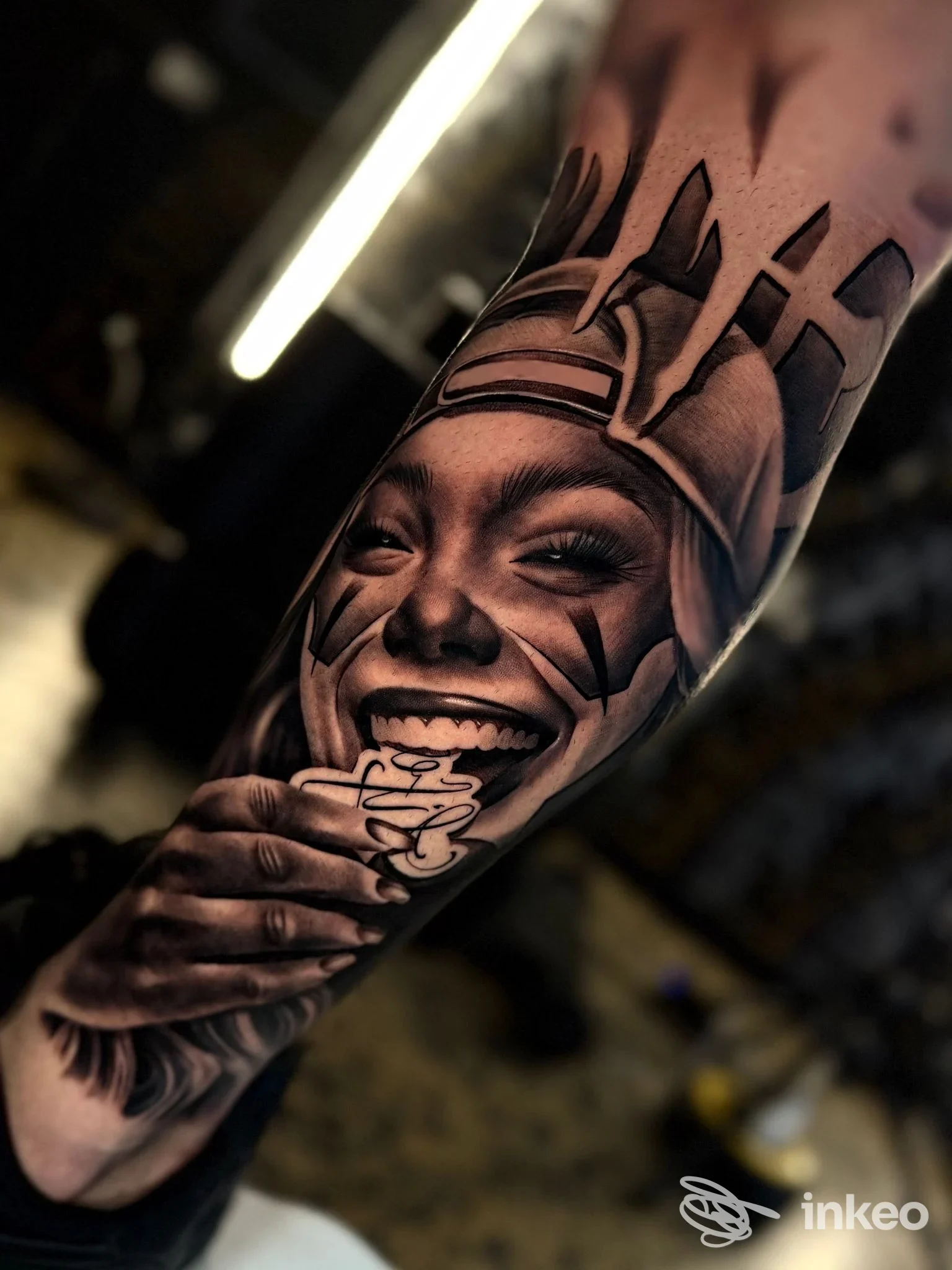 Dettaglio di tatuaggio realistico sul avambraccio raffigurante un volto sorridente con mano, fotografato nello studio Sviringi Tattoo&Piercing a Reggio nell'Emilia.