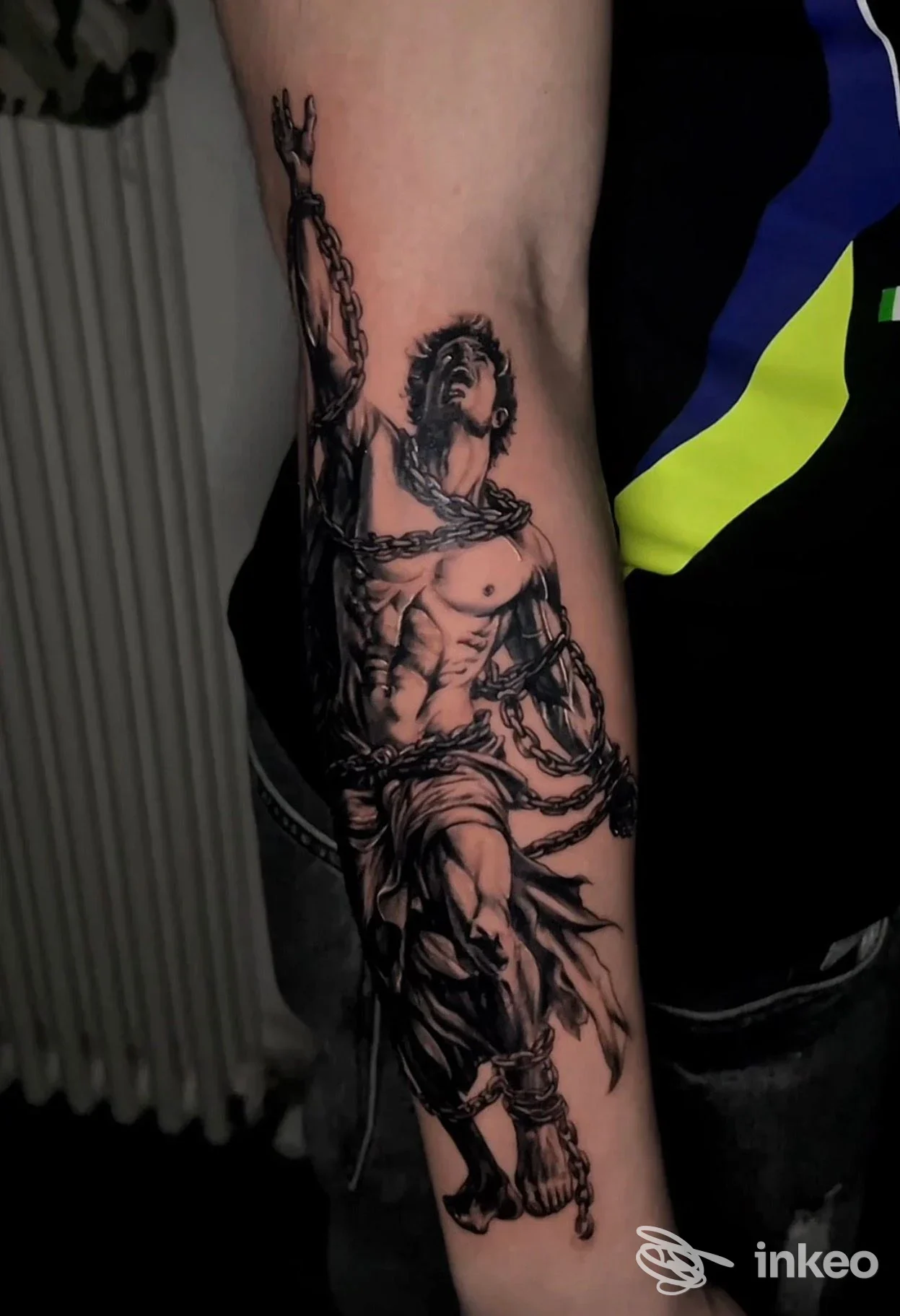 Tatuaggio realistico in bianco e nero su avambraccio raffigurante figura maschile incatenata; lavoro fotografato da 99 INK Tattoo Studio, Case Trebbio.
