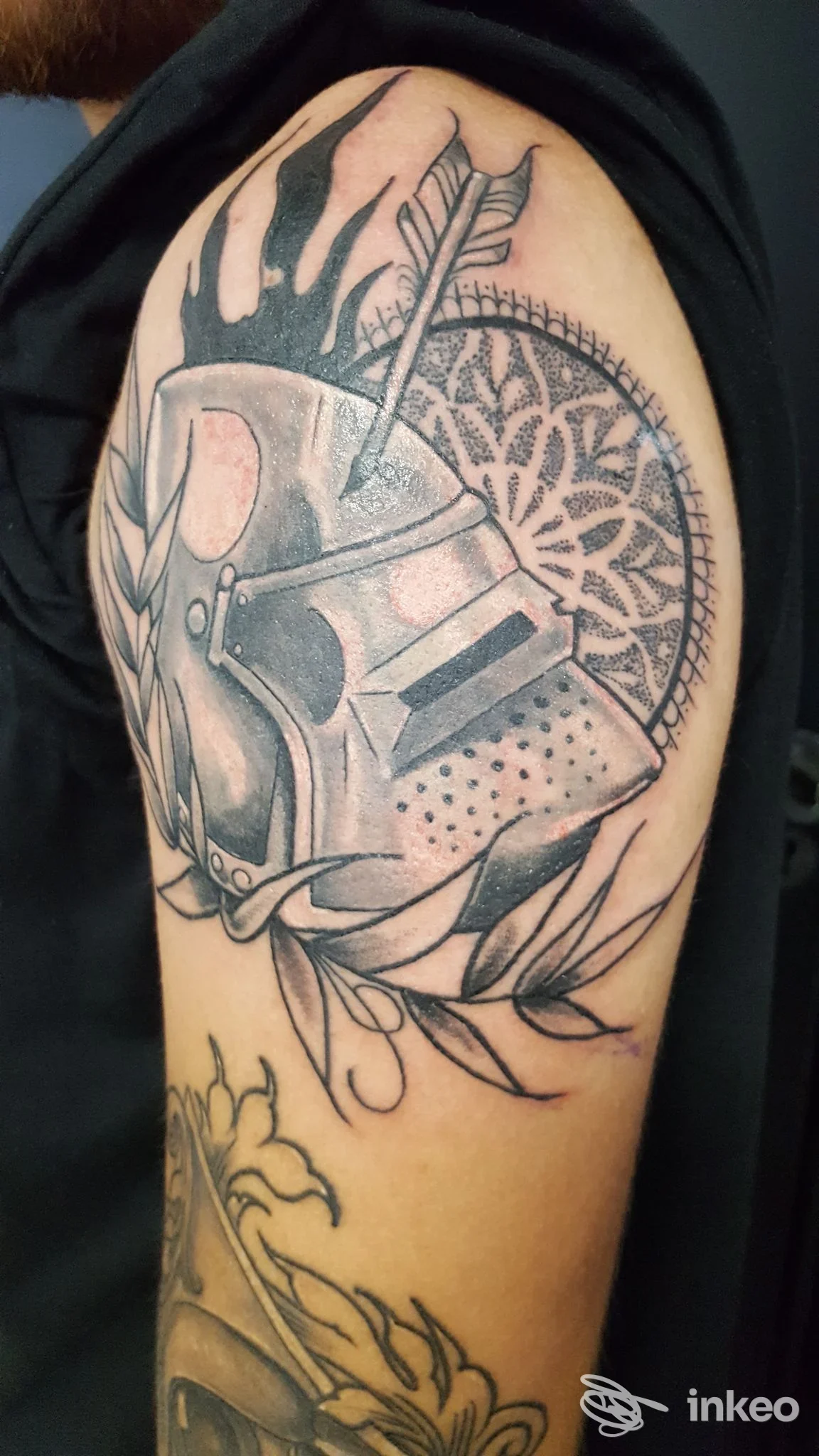 Tatuaggio blackwork su braccio superiore con elmo e mandala, Ludipea Tattoo, San Pietro in Casale.