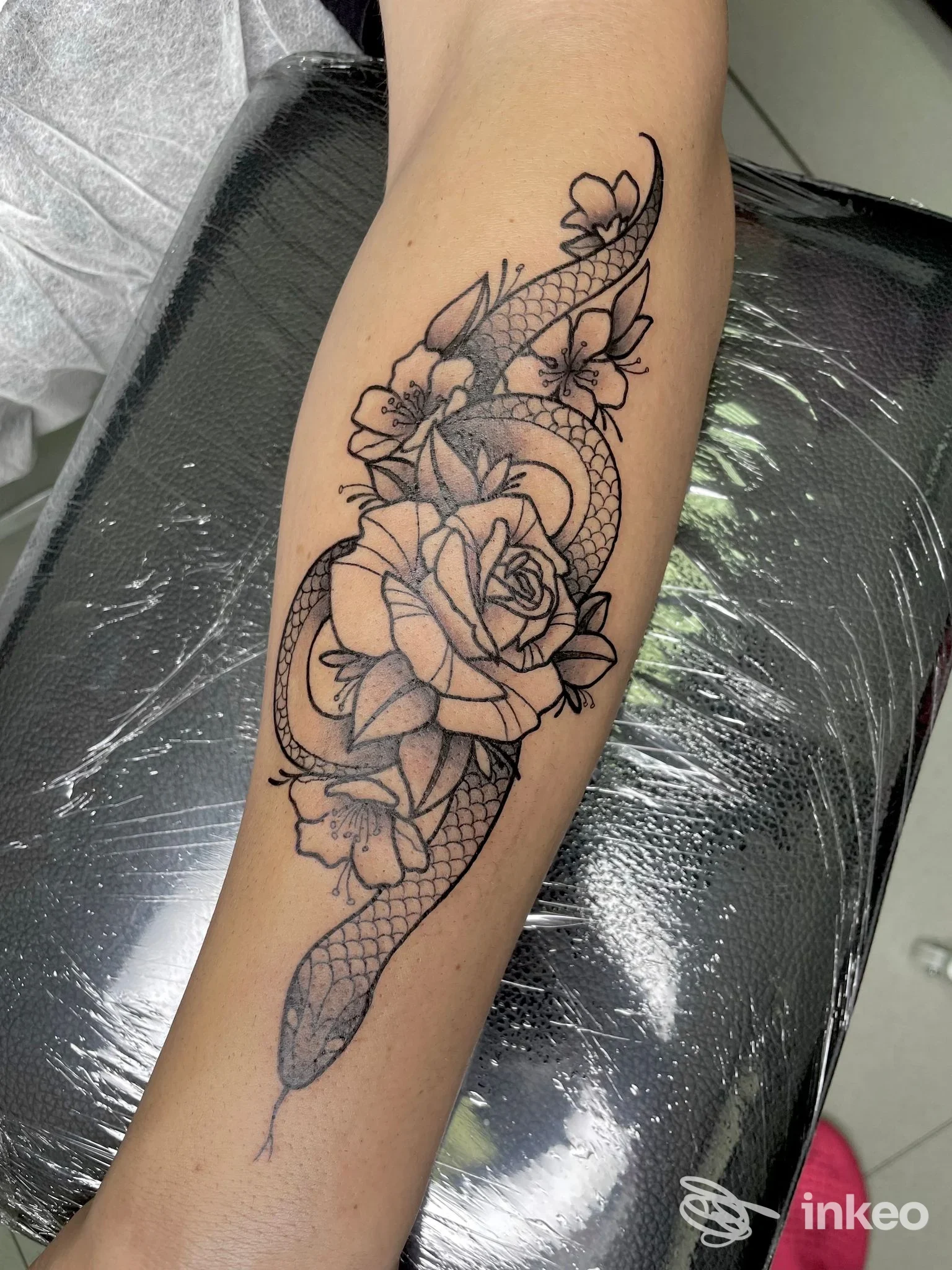 Tatuaggio a serpente e fiori sull'avambraccio, scatto in studio Ellie tattoo, Sassuolo.