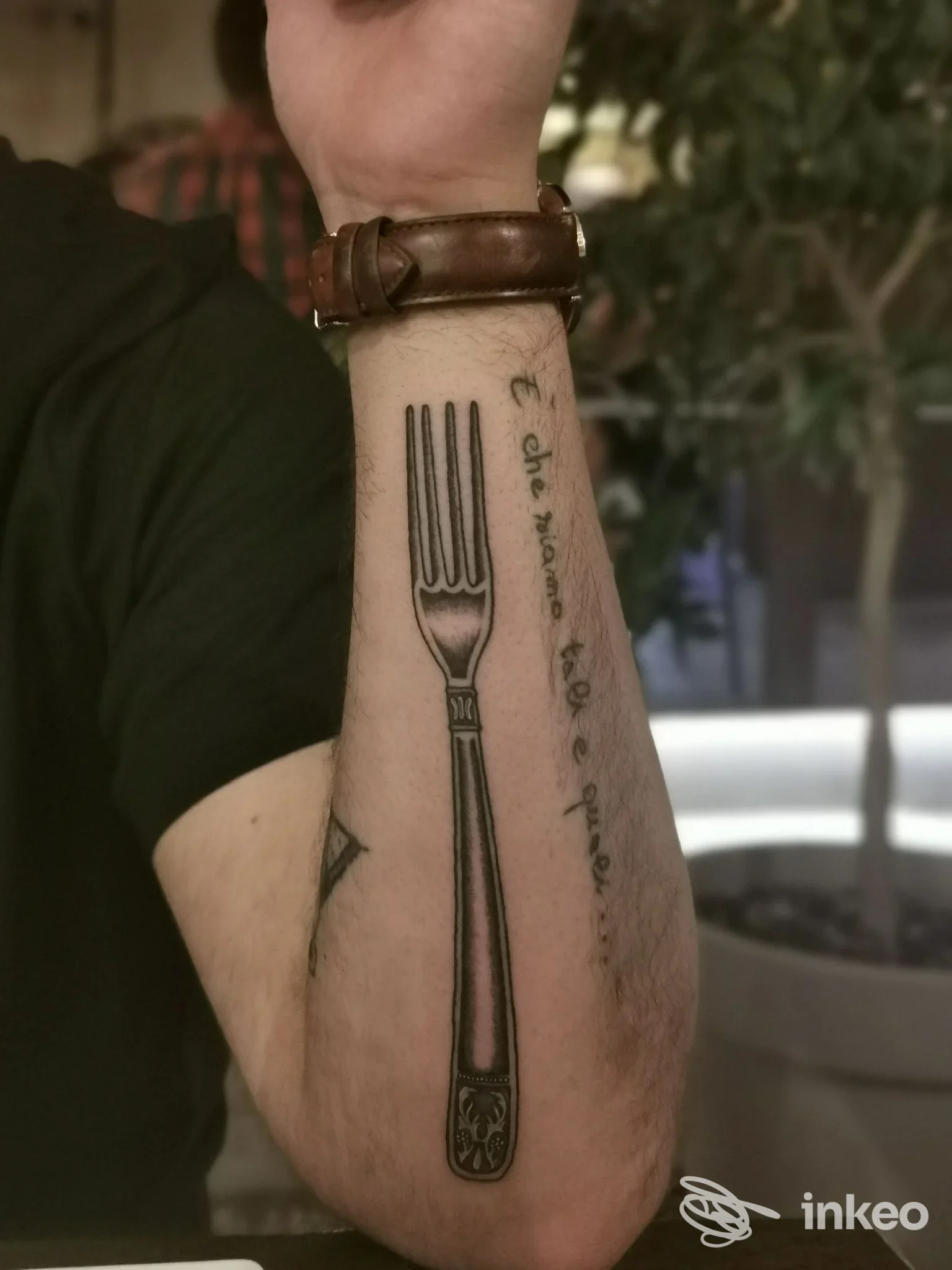 Primo piano di un tatuaggio a forma di forchetta sull'avambraccio, foto per Skinwear Tattoo Shop a Rimini.