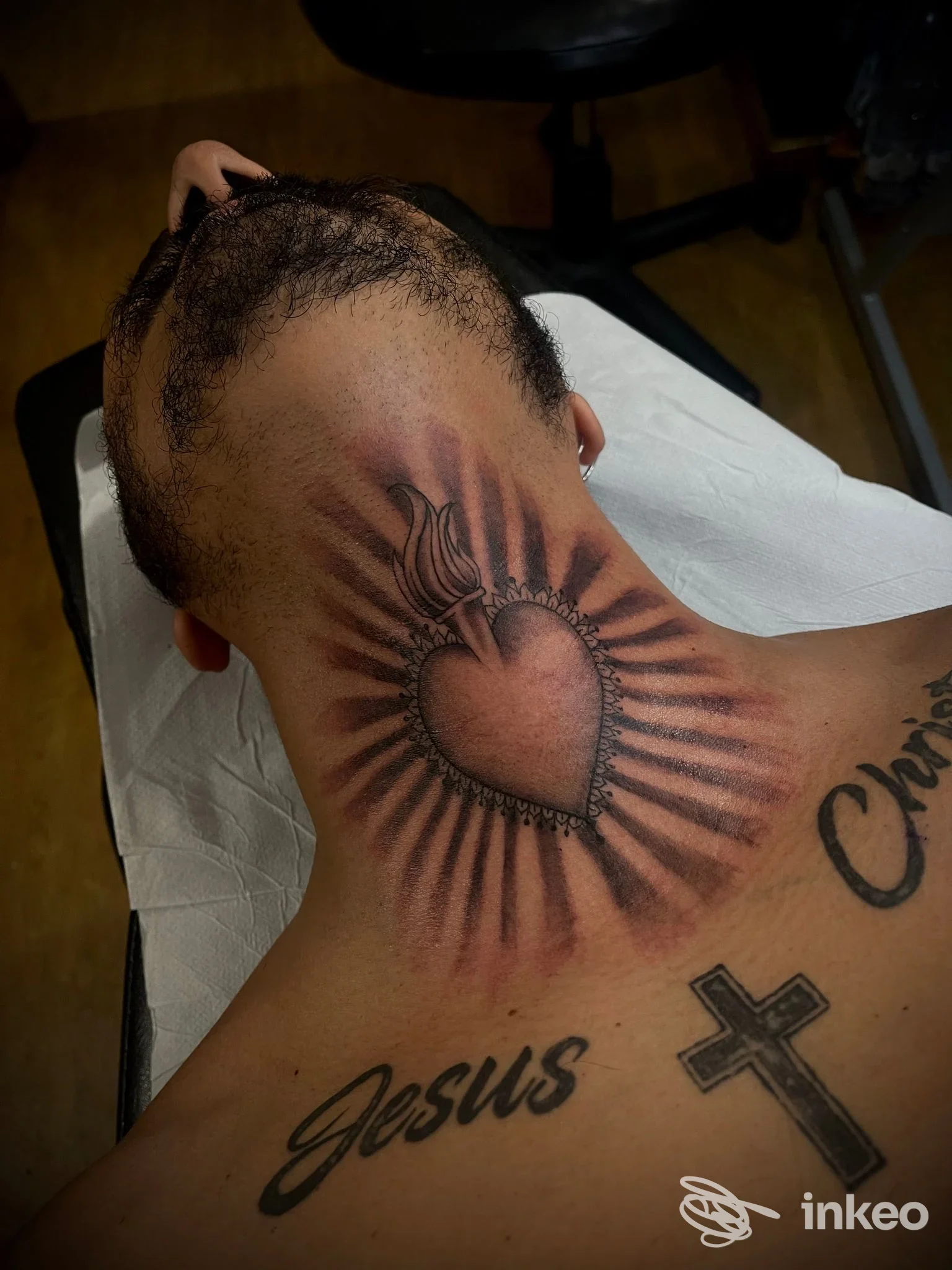 Tatuaggio a forma di cuore con raggi sulla nuca e tatuaggi testuali sulla parte superiore della schiena, foto per Espo Tattoo Studio, Casalecchio di Reno.