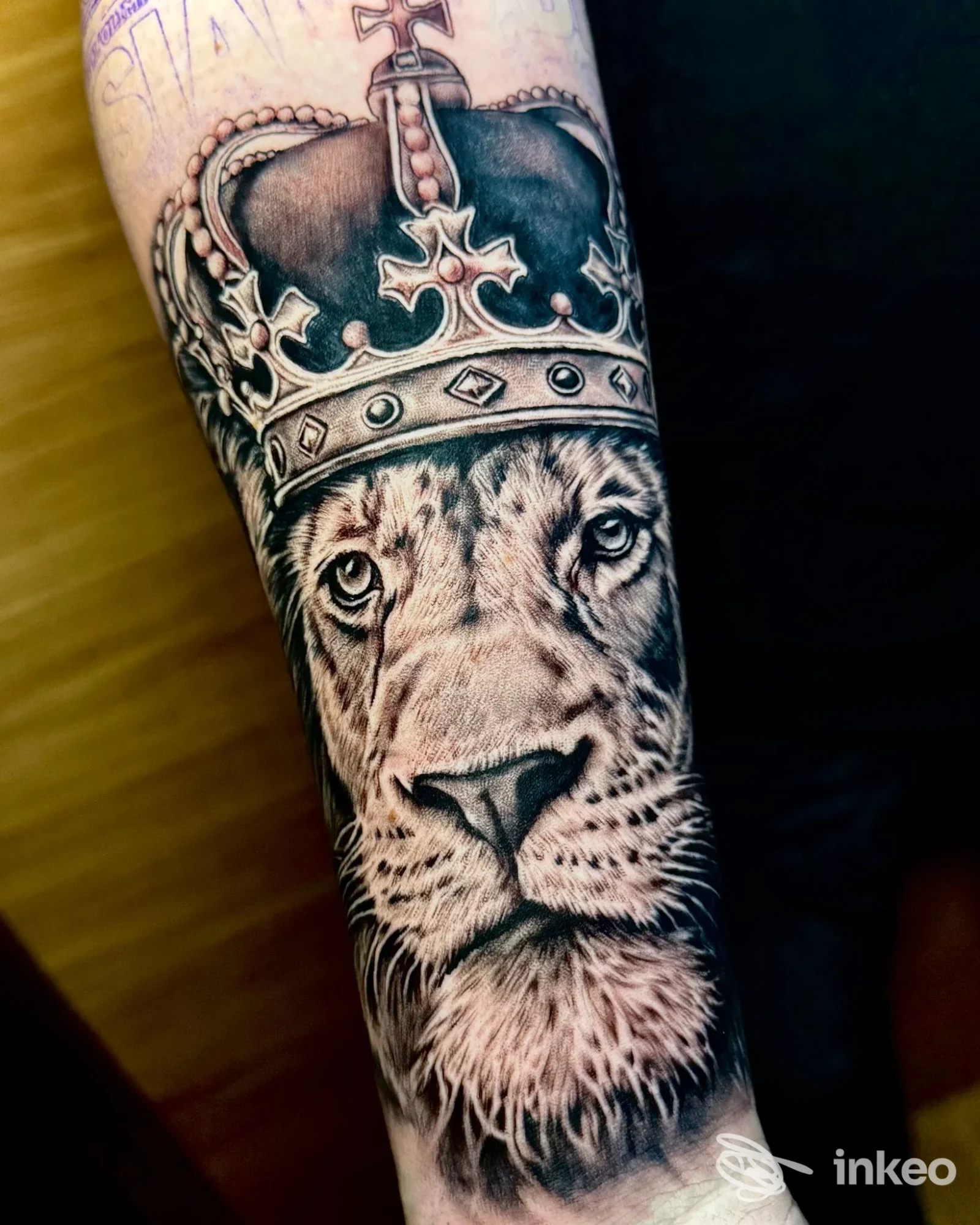 Tatuaggio su avambraccio di un leone con corona, realizzato da Espo Tattoo Studio a Casalecchio di Reno, dettaglio realistico in bianco e nero.