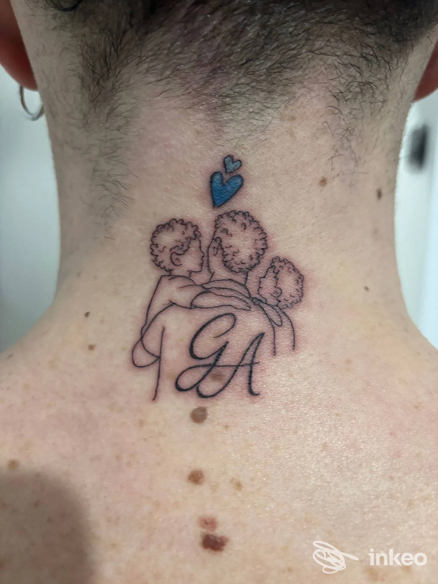 Tatuaggio minimale sulla nuca con iniziali 'GA' e tre figure stilizzate, scatto realizzato per Mary88Ink Tattoo and Piercing a Castelvetro di Modena.