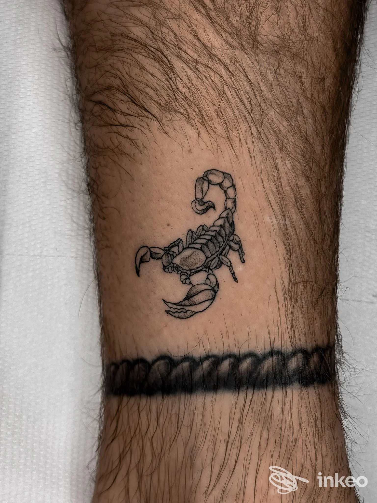 Tatuaggio di uno scorpione e fascia nera sulla caviglia, scatto dettagliato di pelle reale realizzato da Malebolge Tattoo&Piercing a Forlì.