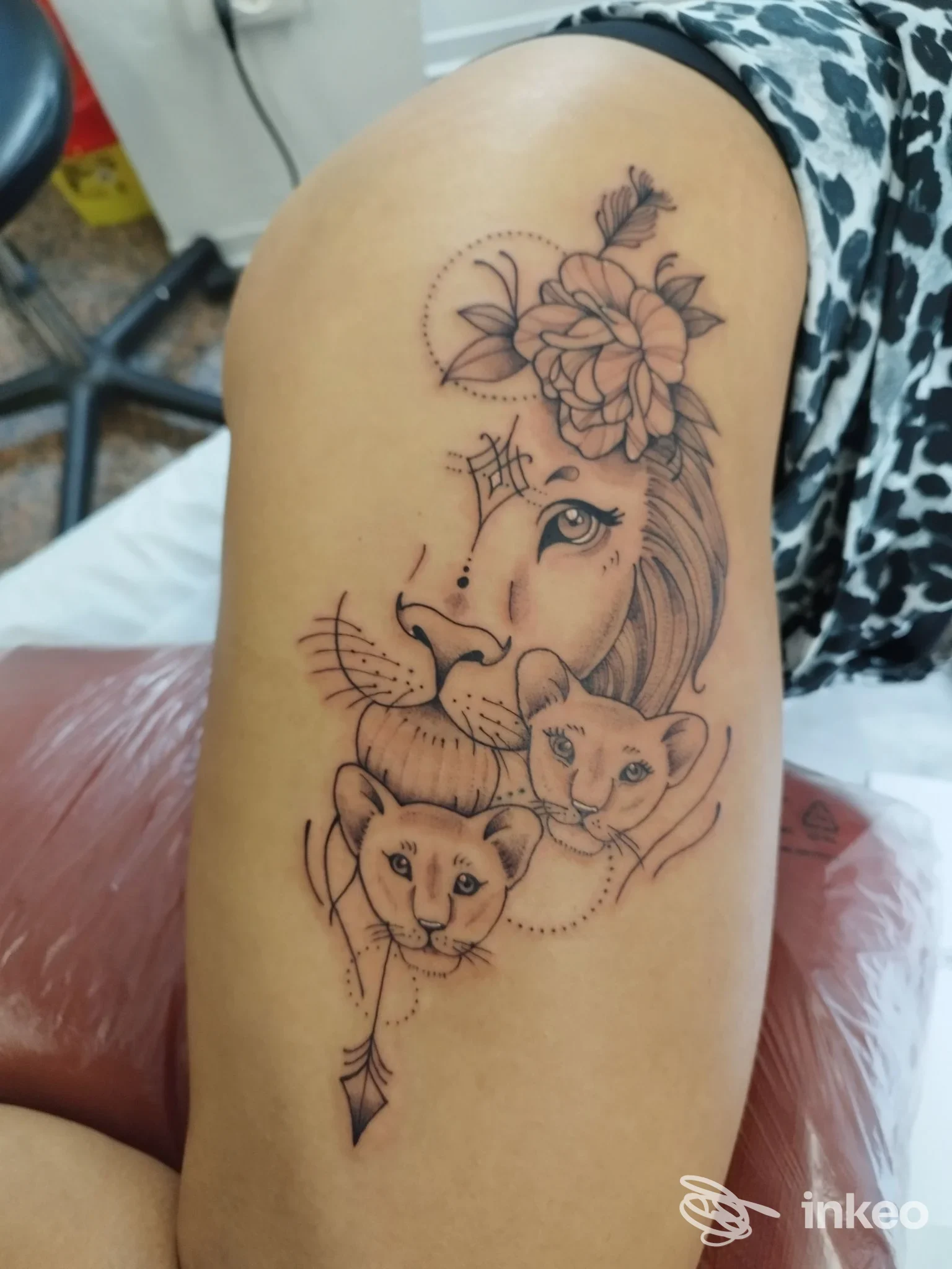 Tatuaggio su braccio superiore con composizione di leone, due cuccioli e fiori in linework e dotwork — Flamingo Riot Tattoo Studio, Cervia.
