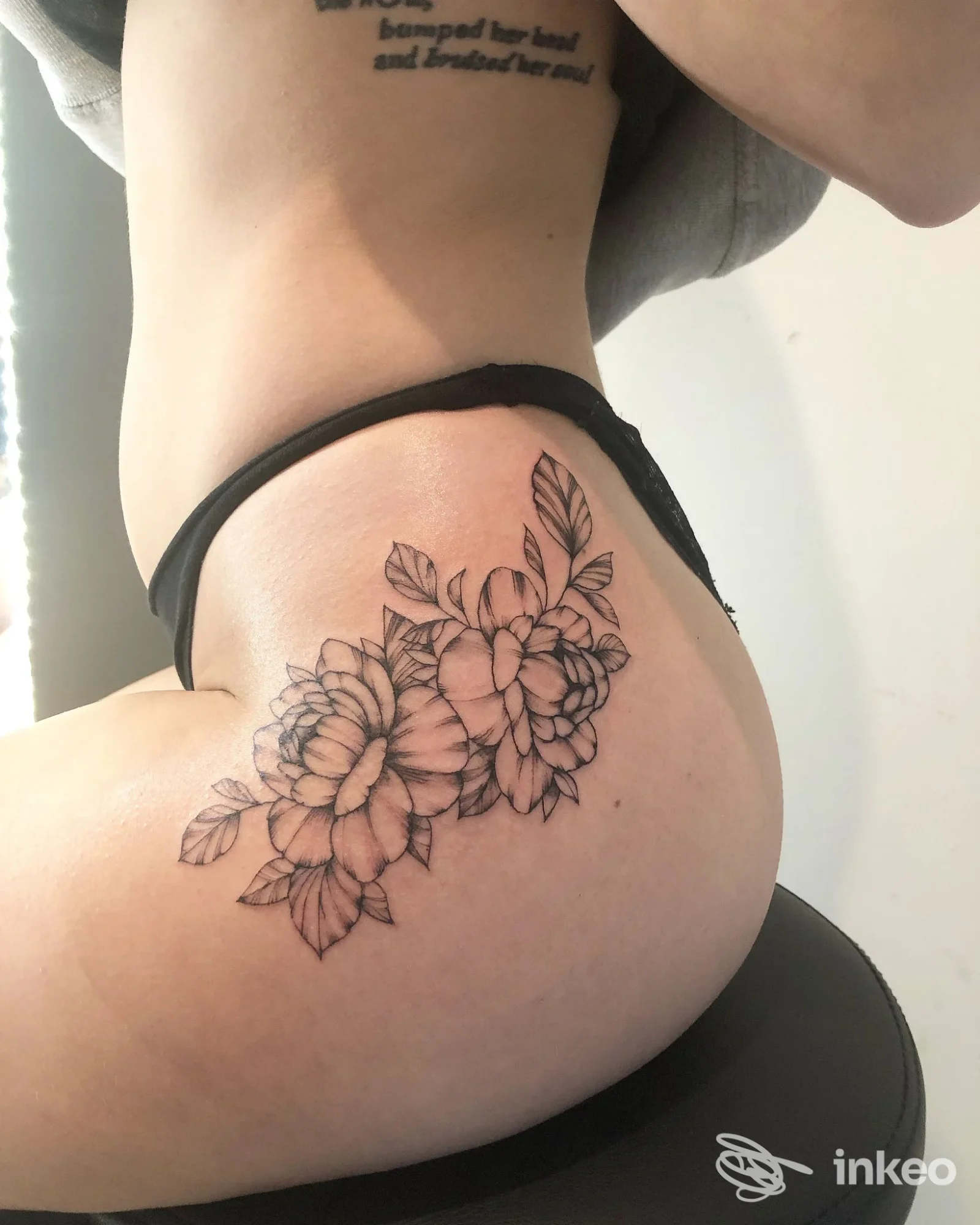 Tatuaggio floreale in linework nero sul fianco/gluteo di una persona, realizzato da Noa Noa Beach Tattoo a Lido di Savio, foto dettaglio.