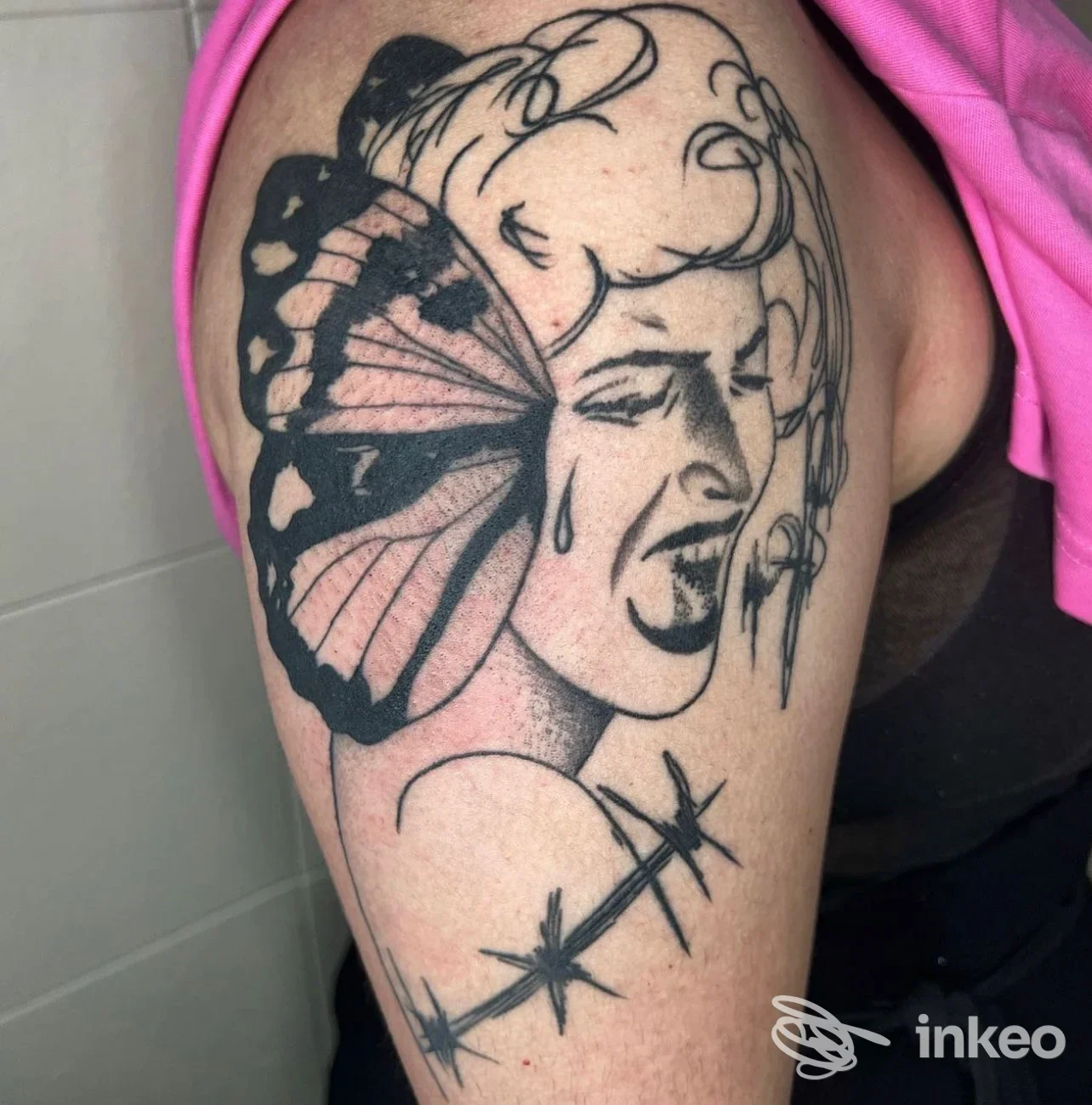 Tatuaggio su braccio con figura femminile e ala di farfalla, e filo spinato; immagine fornita da Sacred Ink Tattoo Parlour, Vignola.