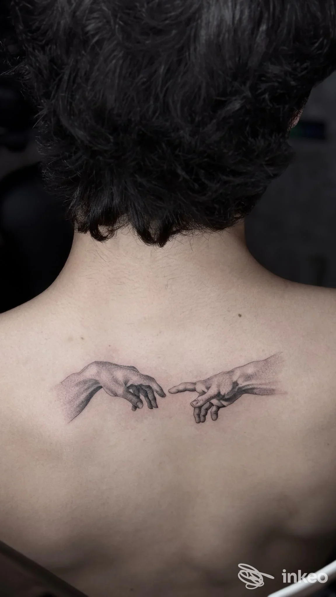 Particolare del tatuaggio sul dorso che raffigura due mani che si sfiorano, eseguito da La Roccia Del Lupo Tattoo Studio a Vidiciatico.