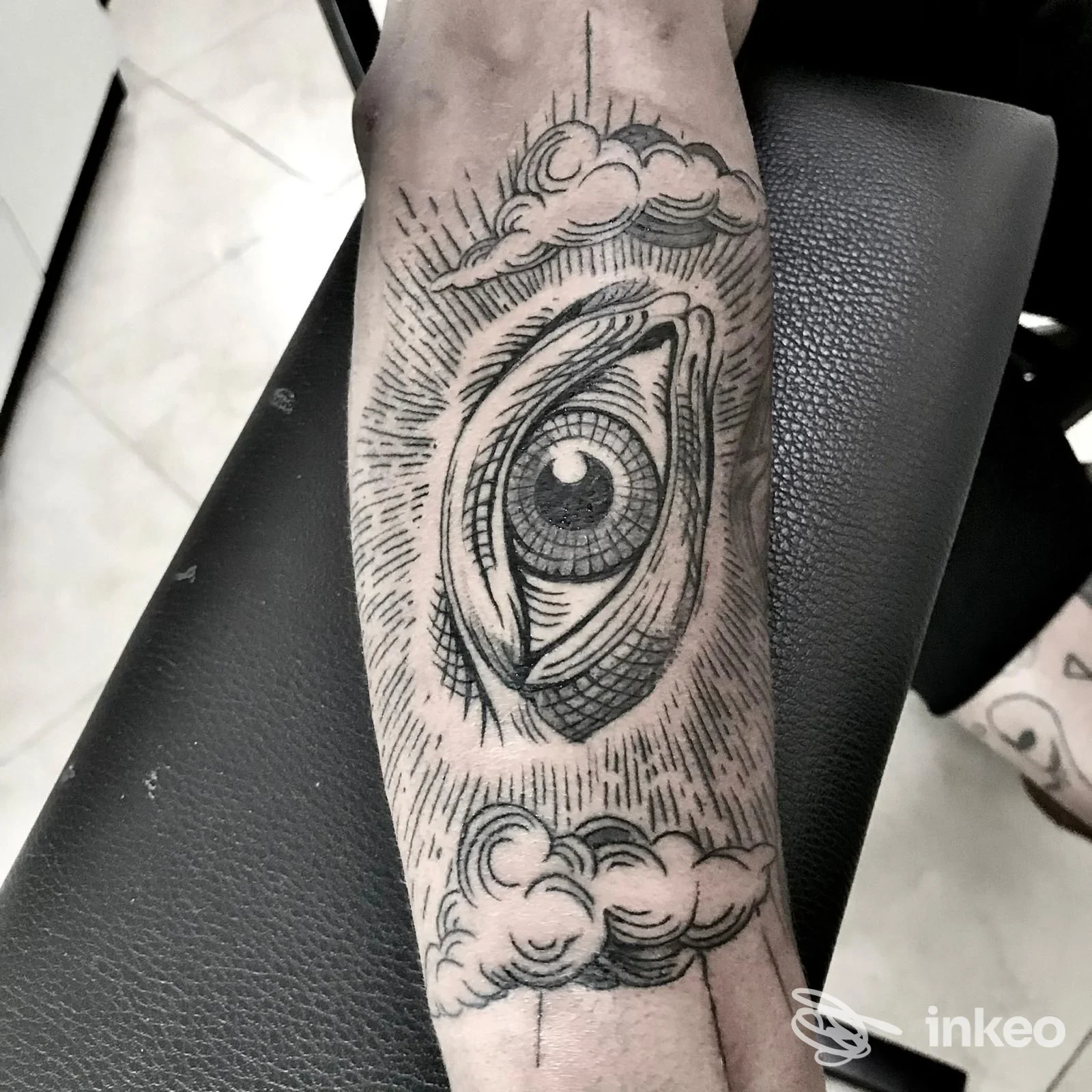 Tatuaggio blackwork di un grande occhio stilizzato con nuvole sull'avambraccio, foto scattata presso Magma Tattoo Studio, Riccione.