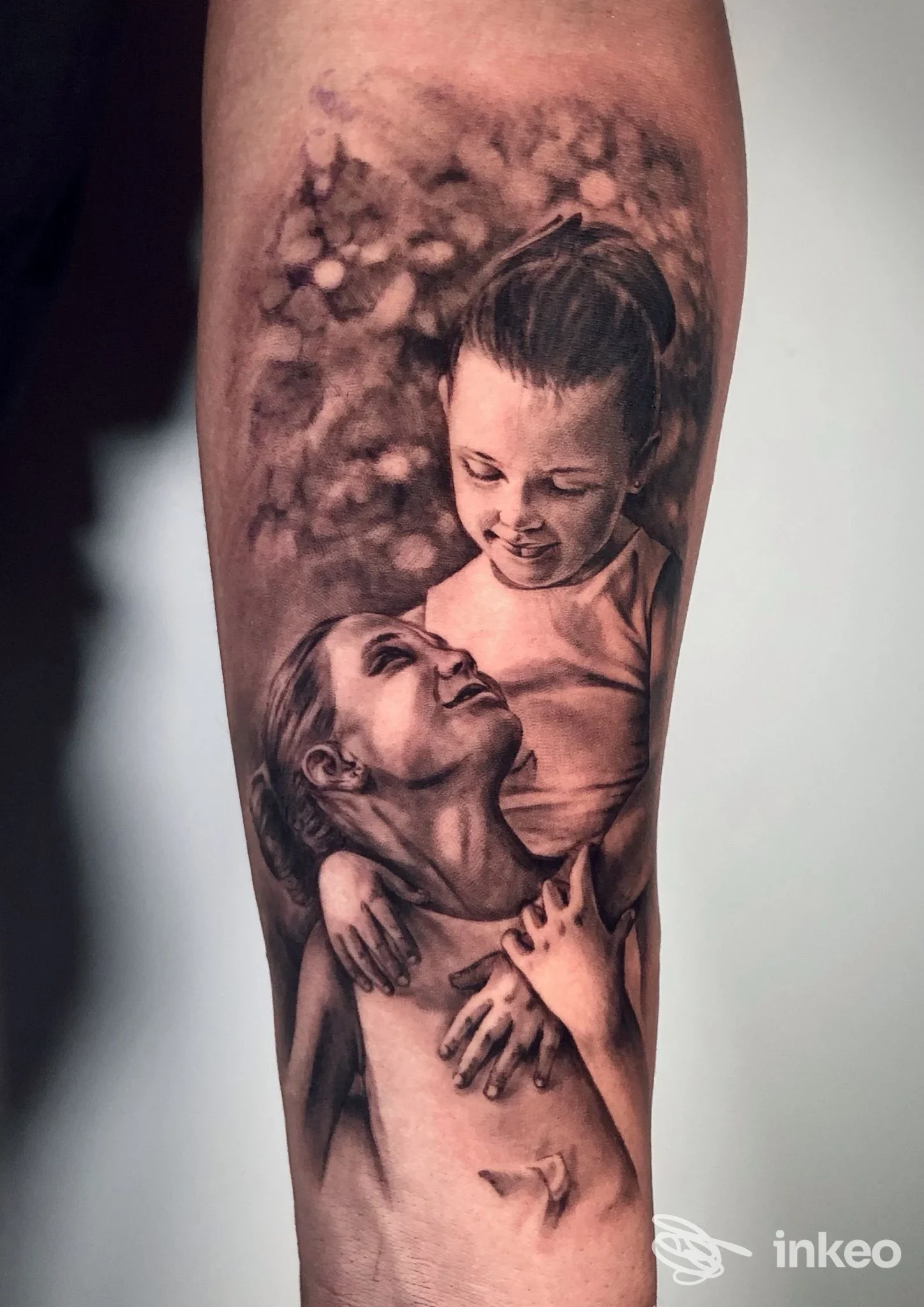 Tattoo realistico su braccio raffigurante due bambini abbracciati.