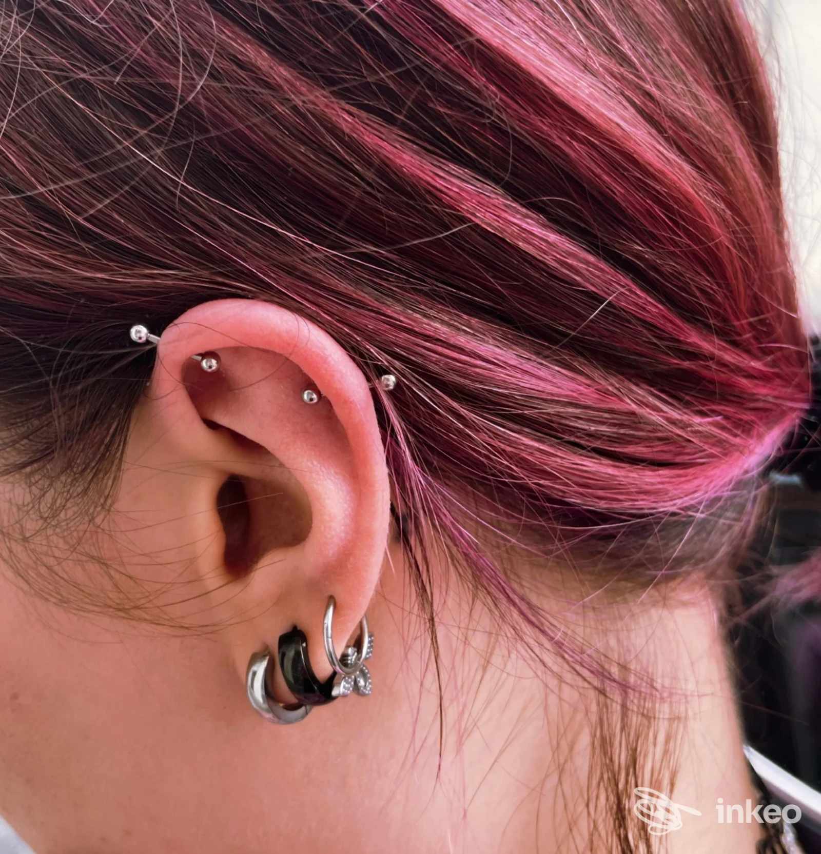 Primo piano di orecchio con più piercing, foto inviata da Nonsolopiercing Studio a Udine, dettagli chiari degli anelli e barbell.