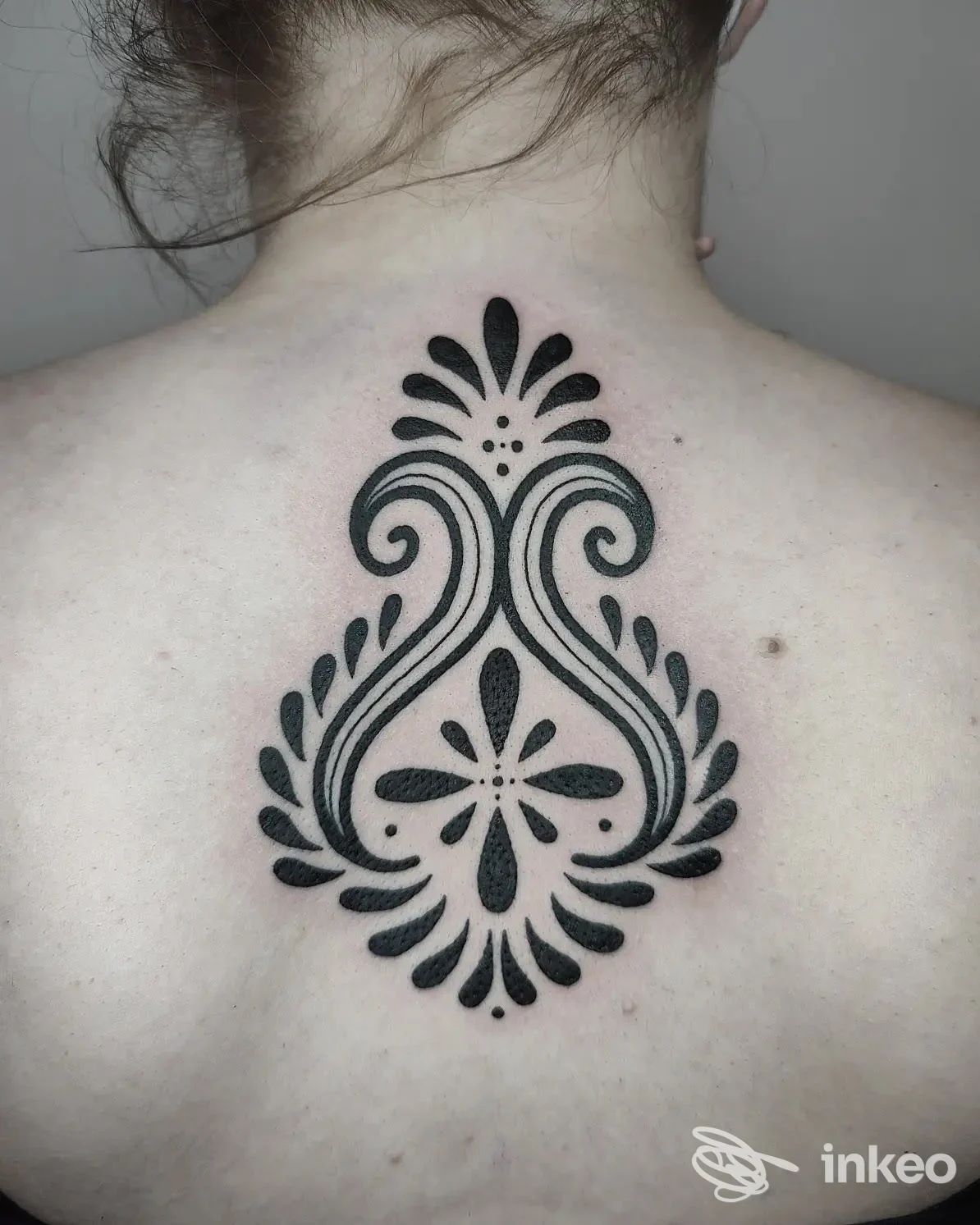Tatuaggio nero ornamentale al centro della parte superiore della schiena, fotografia di SACRED RITES Tattoo&Piercing Studio a Udine.