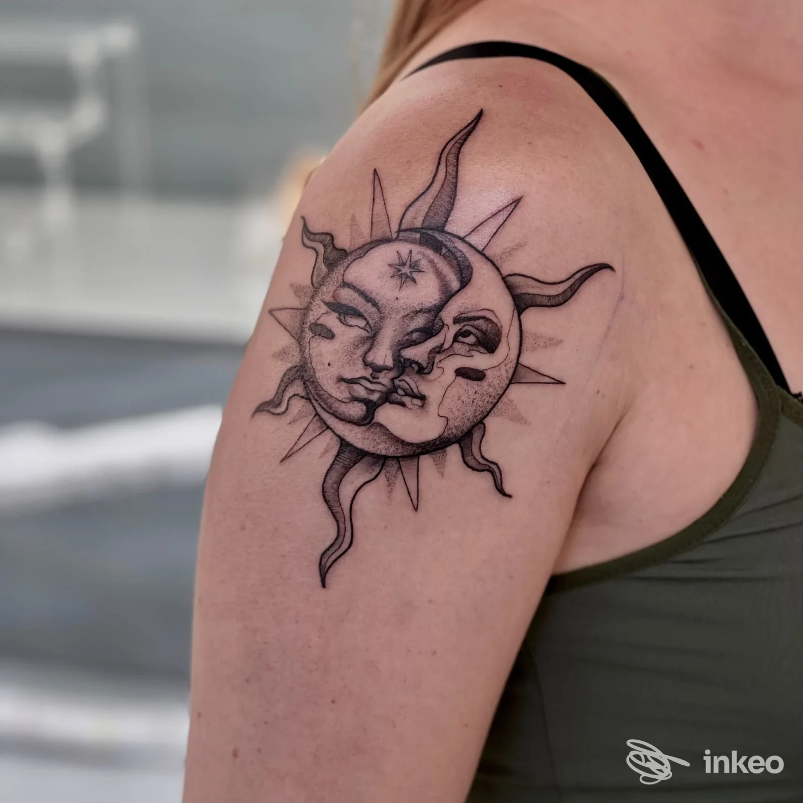 Tatuaggio a inchiostro nero di sole e luna sul deltoide, foto scattata allo studio Essety Piercing Studio a Lignano Sabbiadoro.