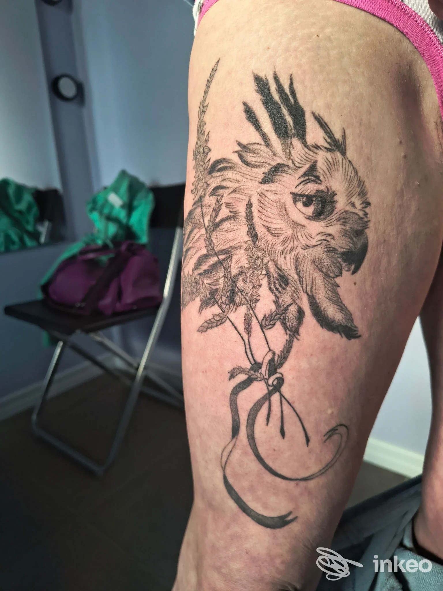 Tatuaggio in nero sulla coscia raffigurante una testa stilizzata con piume e nastri, scattato presso Ivy Tattoo Studio, Gradisca d'Isonzo.