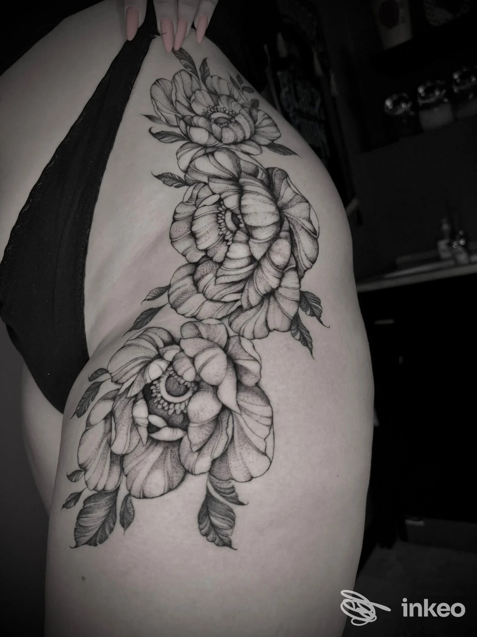 Grande tatuaggio floreale in nero su coscia e fianco, foto dettagliata del lavoro realizzato presso lo studio Badinka Tattoo a Maniago.