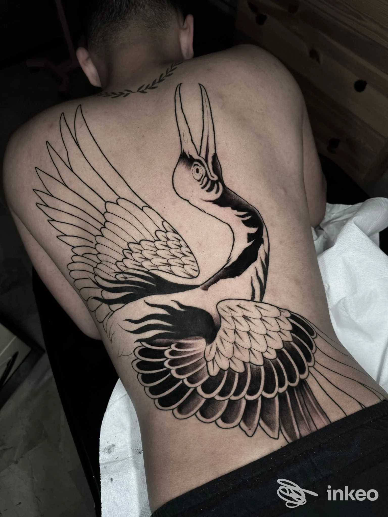Grande tatuaggio di gru in blackwork sulla schiena, realizzato da Badinka Tattoo a Maniago.