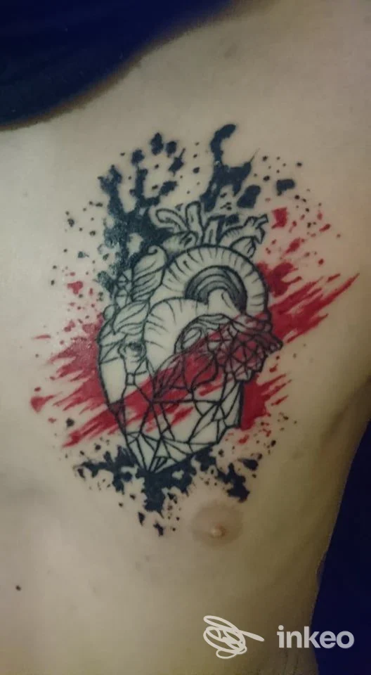 Tatuaggio a cuore anatomico con linee nere e schizzi rossi sul torace, foto per Yomi Tattoo Studio, San Vito al Tagliamento.