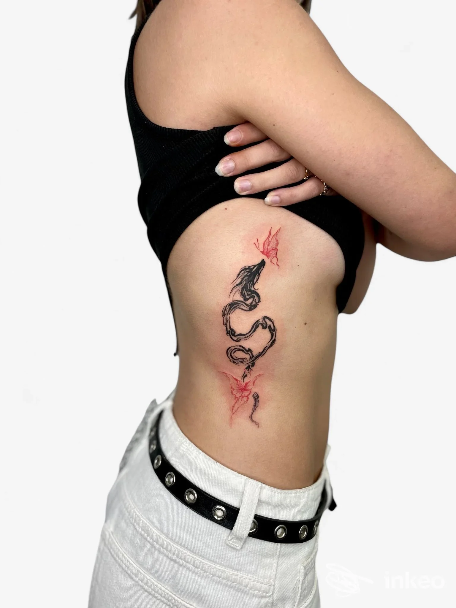 Tatuaggio nero con dettagli rossi sul fianco, fotografato per Tattoo Supreme Trieste a Trieste.
