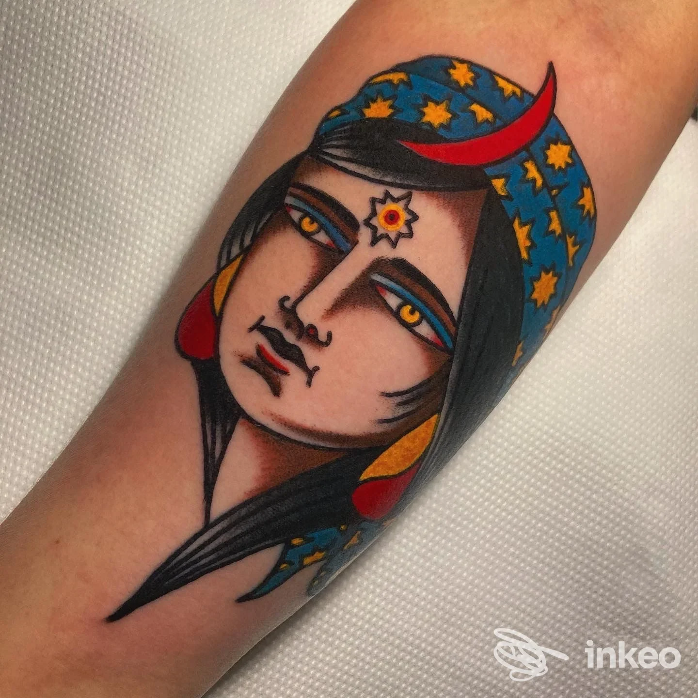 Tatuaggio neo-traditional su avambraccio: volto femminile stilizzato con copricapo a stelle e mezzaluna, ELECTRICAT TATTOOING, Trieste.