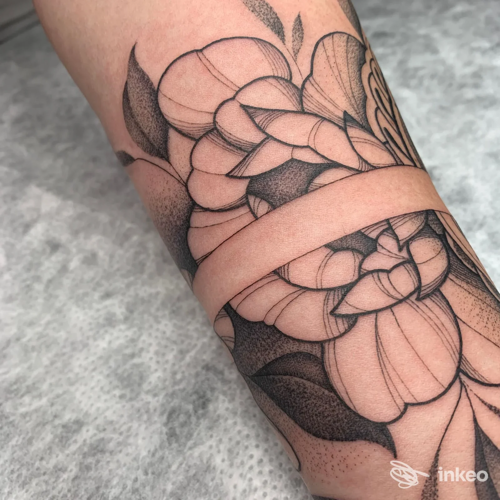 Primo piano di un tatuaggio floreale in nero sull'avambraccio, linework e dotwork puliti. La Burra Tattoo Studio, Cividale del Friuli.
