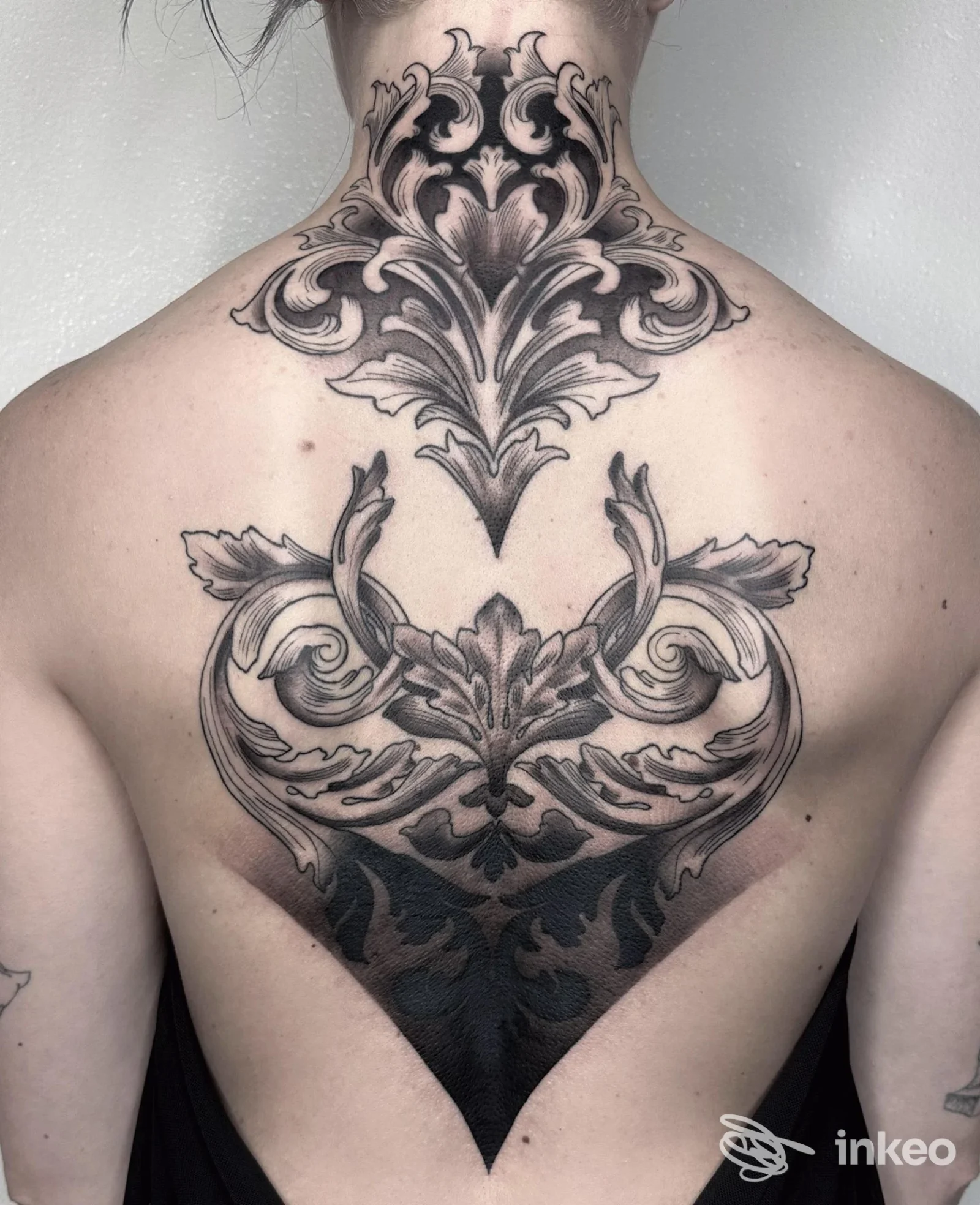 Grande tatuaggio ornamentale in bianco e nero su nuca e parte alta della schiena, fotografia fornita da NERO tattoo atelier, Duino Aurisina.