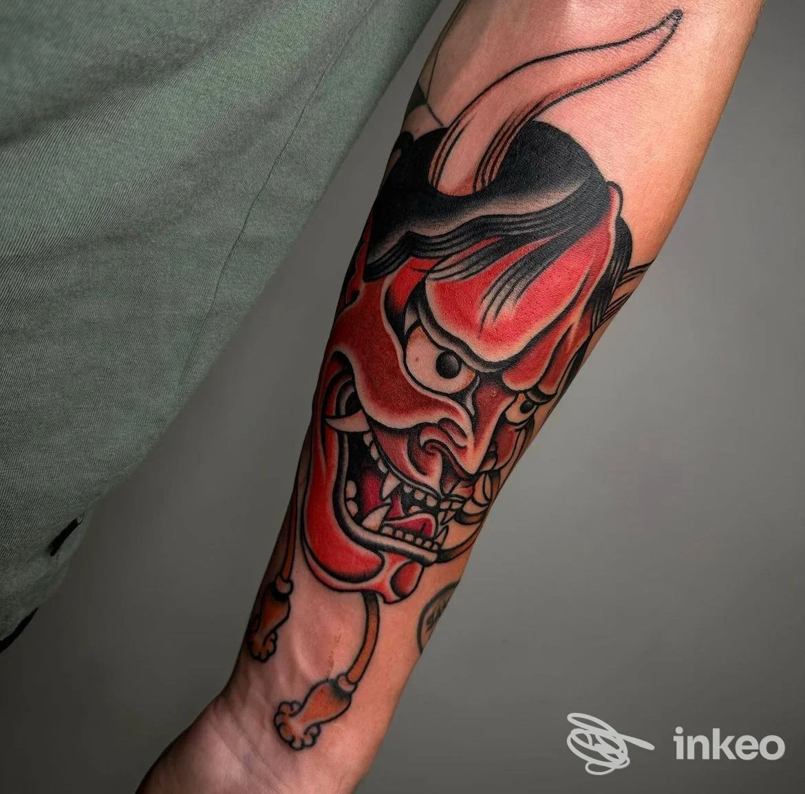 Tatuaggio a maschera oni rosso e nero sull'avambraccio, fotografato per Outsiders-tattooshop a Udine.