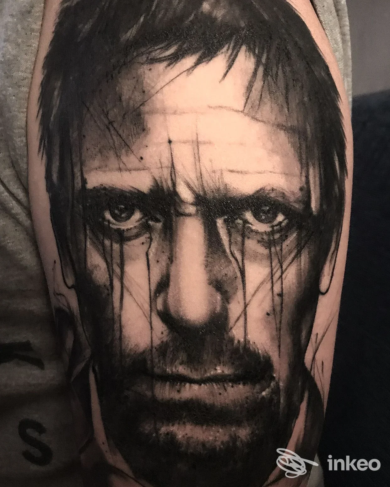 Tatuaggio realistico in bianco e nero di un volto applicato sul bicipite, SGB Tatuaggi e Piercing, Gorizia.