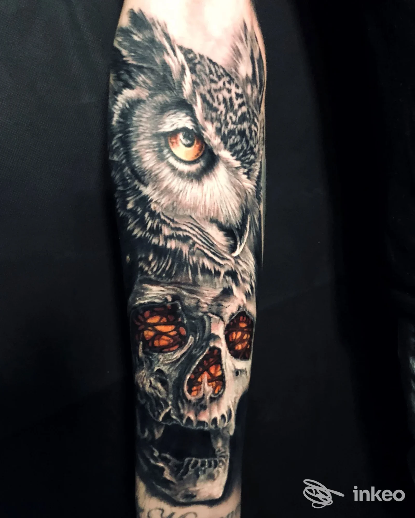 Tatuaggio realistico su avambraccio raffigurante un gufo e un teschio con dettagli cromatici, opera di Ink Empire Tattoo & Piercing, Grado.
